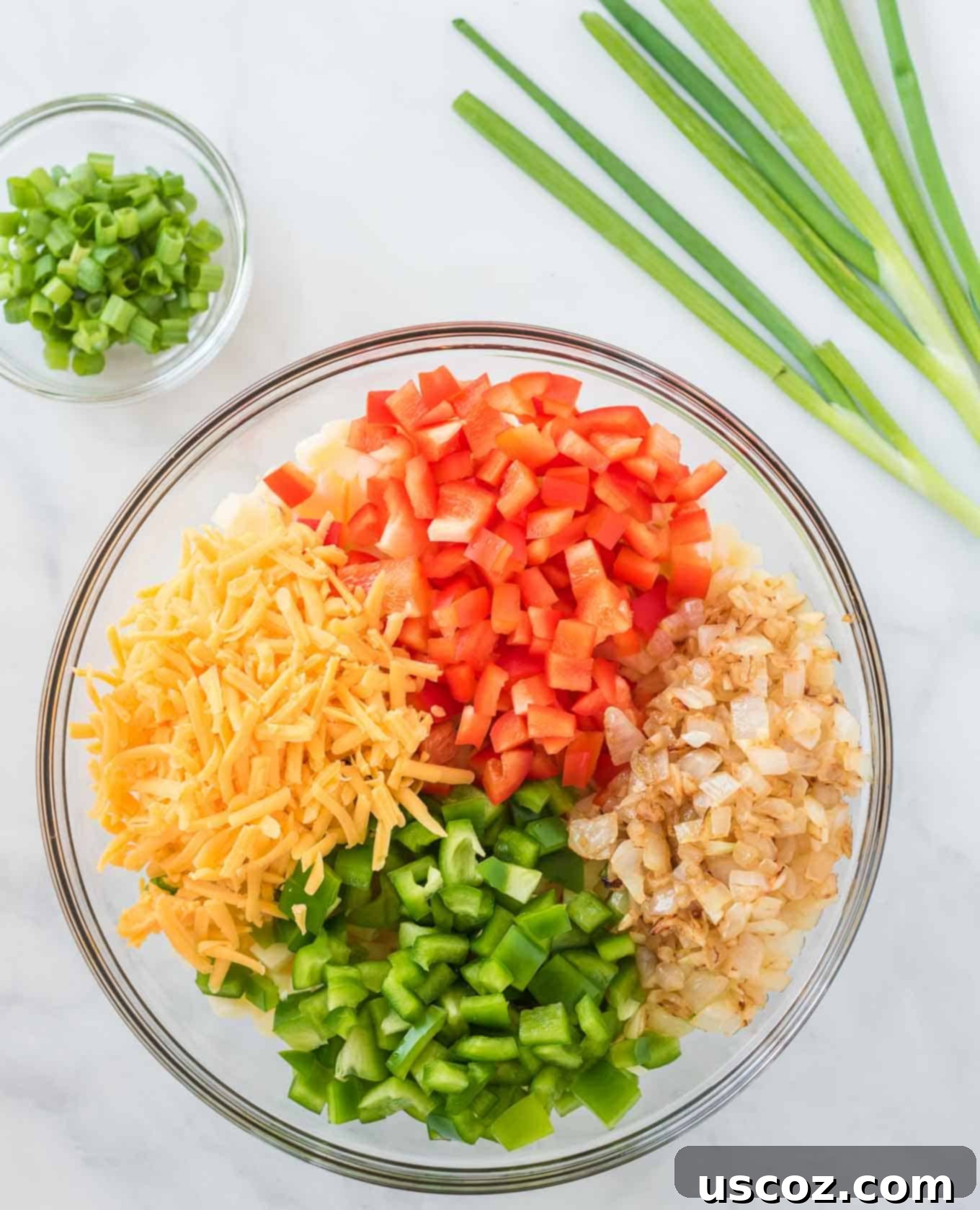 Golden Hash Brown Egg Bake 5 potatoes, bell pepper, onion, and cheese together in a glass mixing bowl