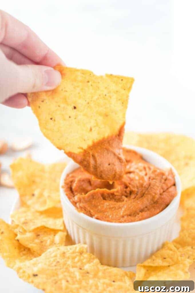 Creamy Plant-Based Queso 11 a chip dipped in a white ramekin of vegan queso