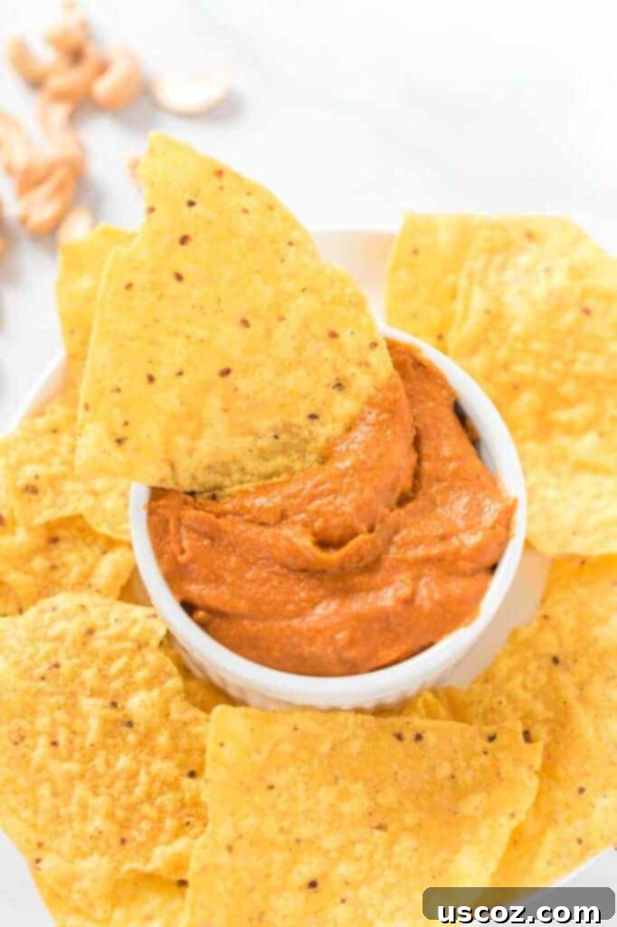 Creamy Plant-Based Queso 10 a chip dipped in a white ramekin of vegan queso