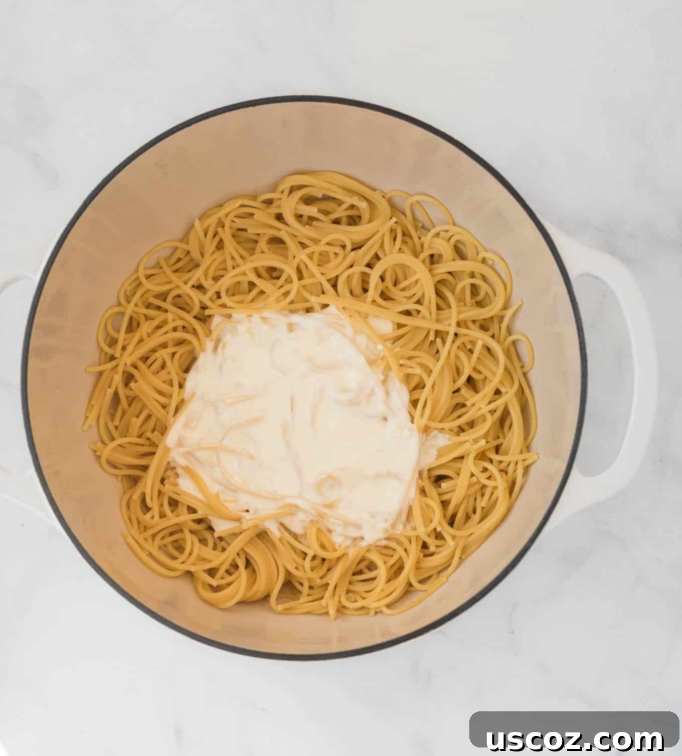 Velvety Cream Cheese Pasta 6 Spaghetti noodles freshly drained with creamy white cream cheese sauce poured over them in a large pot.