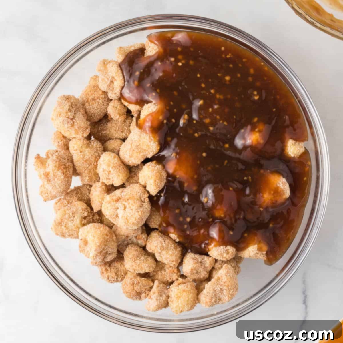 Sticky Teriyaki Cauliflower Bites 12 Freshly baked crispy cauliflower being tossed with homemade teriyaki sauce in a large bowl, ensuring even coating.