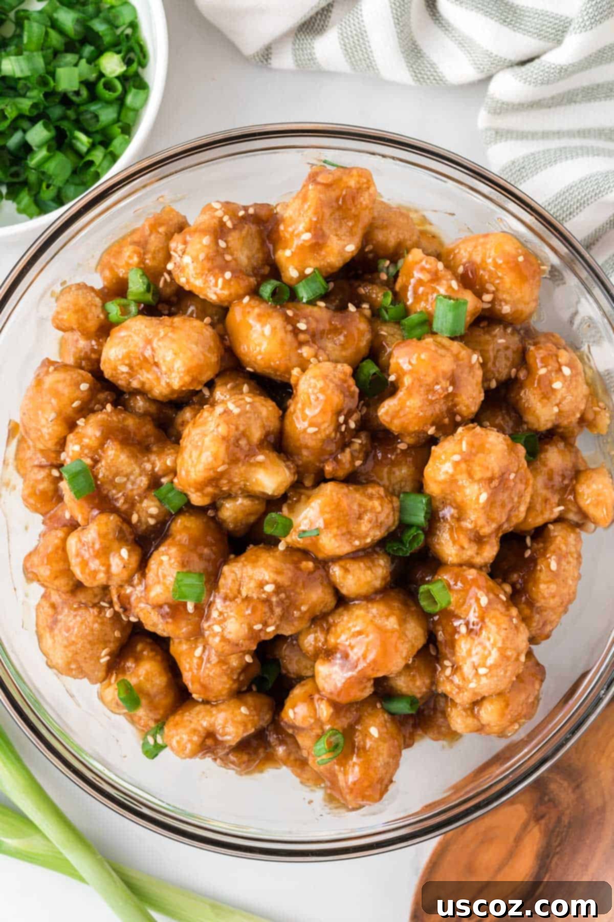 Sticky Teriyaki Cauliflower Bites 13 A beautifully presented bowl of teriyaki cauliflower, generously topped with green onions and sesame seeds, showcasing the dish ready to be savored.