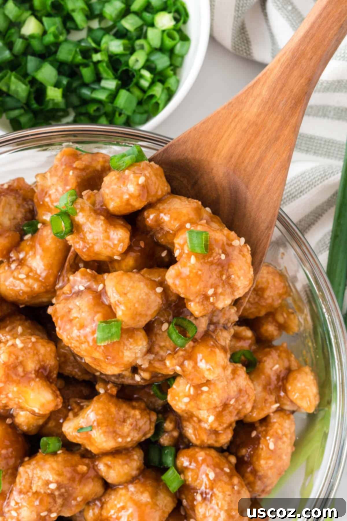 Sticky Teriyaki Cauliflower Bites 3 A bowl of glossy teriyaki cauliflower topped with vibrant green onions and toasted sesame seeds, ready to be served.