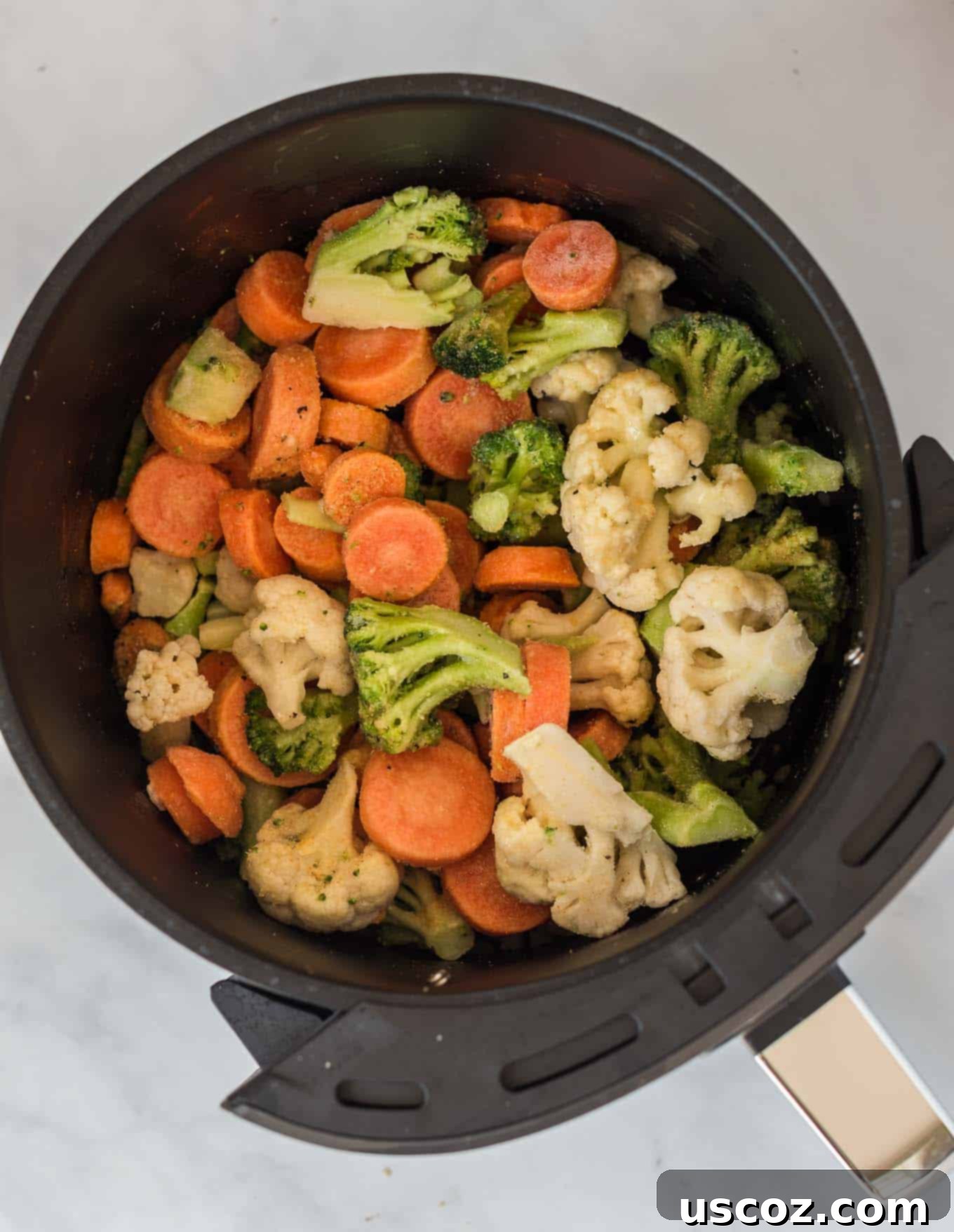 Perfect Air Fryer Frozen Vegetables 3 Frozen mixed vegetables are spread evenly in an air fryer basket, ready for cooking.