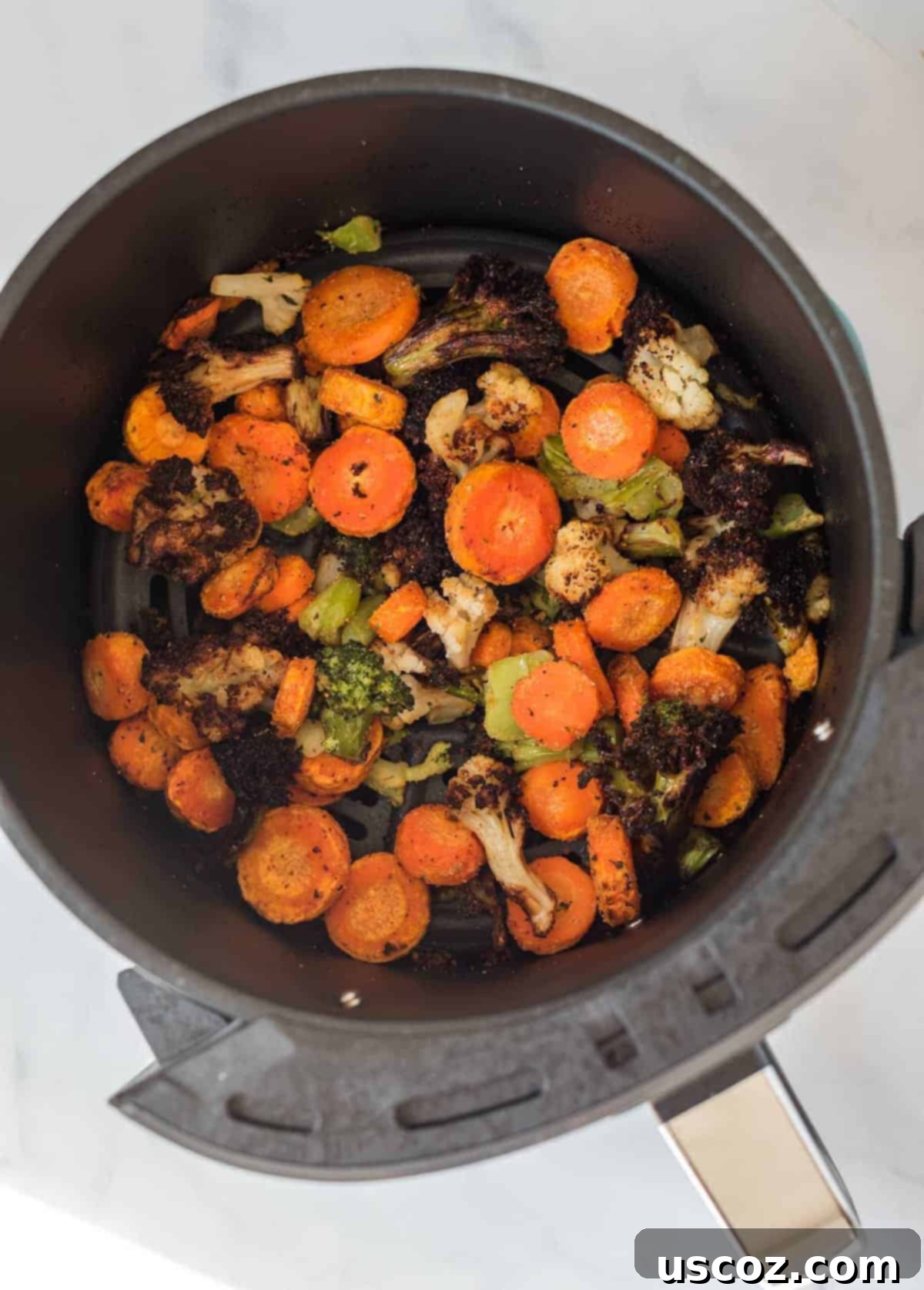 Perfect Air Fryer Frozen Vegetables 4 Crispy, air-fried mixed vegetables are scooped from the air fryer basket, showing their perfectly roasted texture.