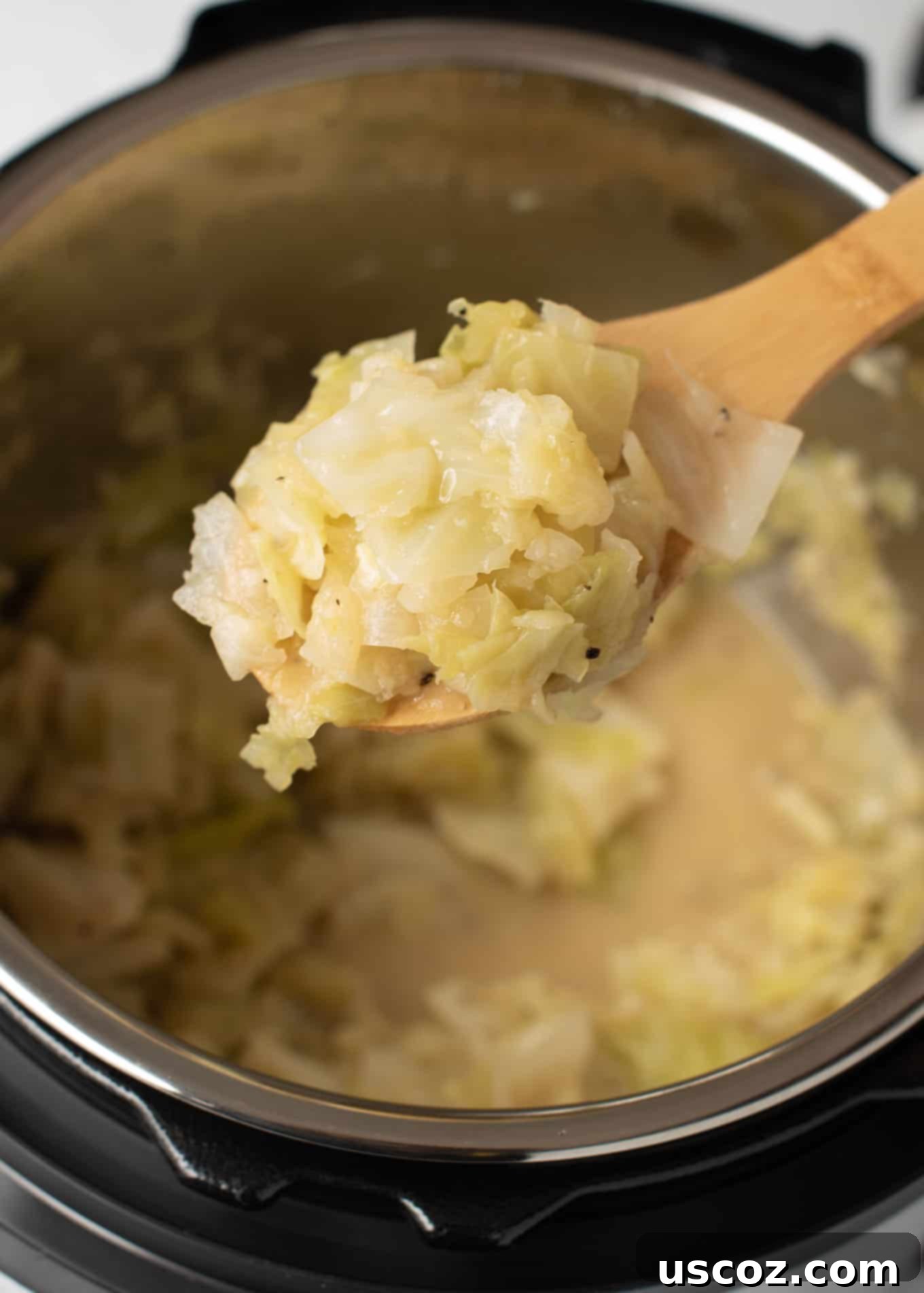 Savory Instant Pot Cabbage 8 A spoon taking a scoop of buttered cabbage from the Instant Pot with steam rising