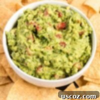Your New Favorite Guacamole Recipe 12 guacamole with tomatoes in a serving bowl surrounded by tortilla chips