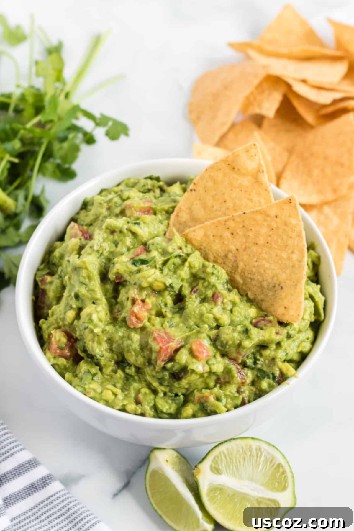 Your New Favorite Guacamole Recipe 10 A close-up shot of a tortilla chip being dipped into a bowl of creamy guacamole, highlighting its vibrant texture.