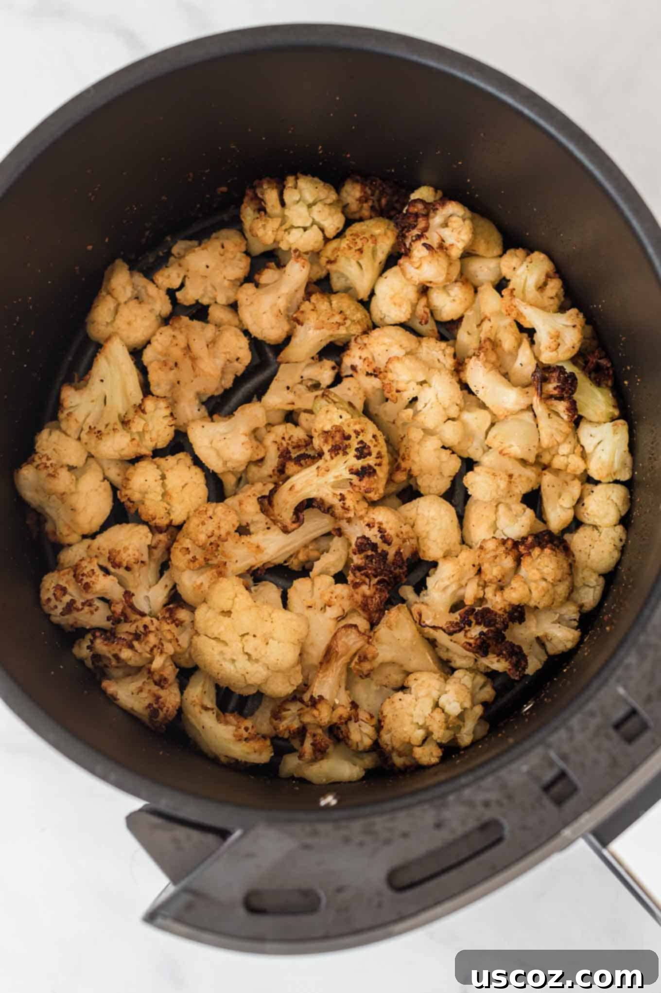Crispy Air Fryer Frozen Cauliflower 4 Perfectly air fried frozen cauliflower, golden brown and wonderfully crispy, still nestled inside the air fryer basket after cooking.