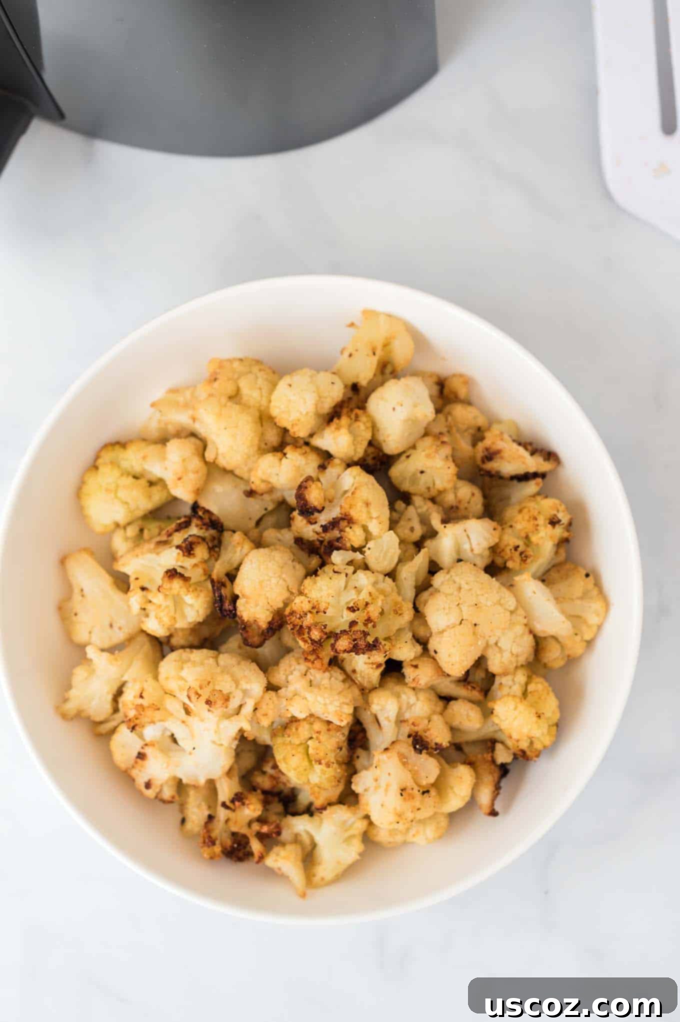 Crispy Air Fryer Frozen Cauliflower 6 A generous serving of perfectly cooked air fryer frozen cauliflower presented in a clean white ceramic bowl, ready to be enjoyed as a healthy and flavorful side dish.
