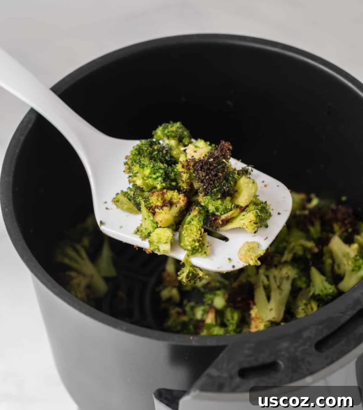 Crispy Air Fryer Frozen Broccoli 6 a white spatula with a scoop of roasted broccoli