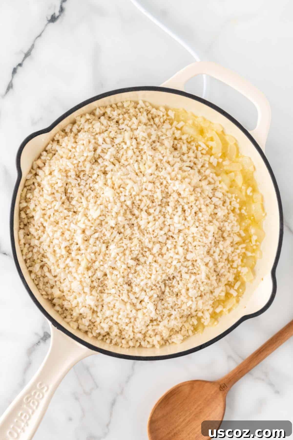 Zesty Cilantro Lime Cauliflower Rice 8 Fresh riced cauliflower added to a skillet with sautéed onions and garlic, ready to be cooked.