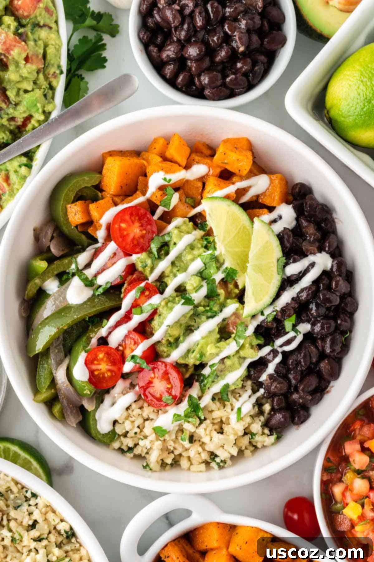 Low-Carb Cauliflower Rice Burrito Bowl 2 Delicious cauliflower rice burrito bowl with black beans, fajita veggies, sweet potatoes, and guacamole ready to eat