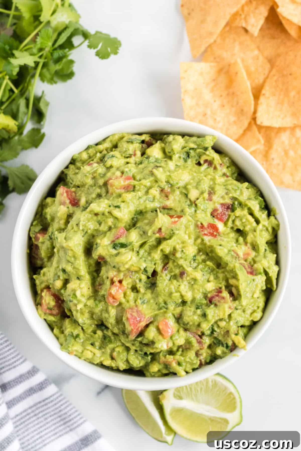 Low-Carb Cauliflower Rice Burrito Bowl 16 Close-up of fresh homemade guacamole with diced tomatoes in a white bowl