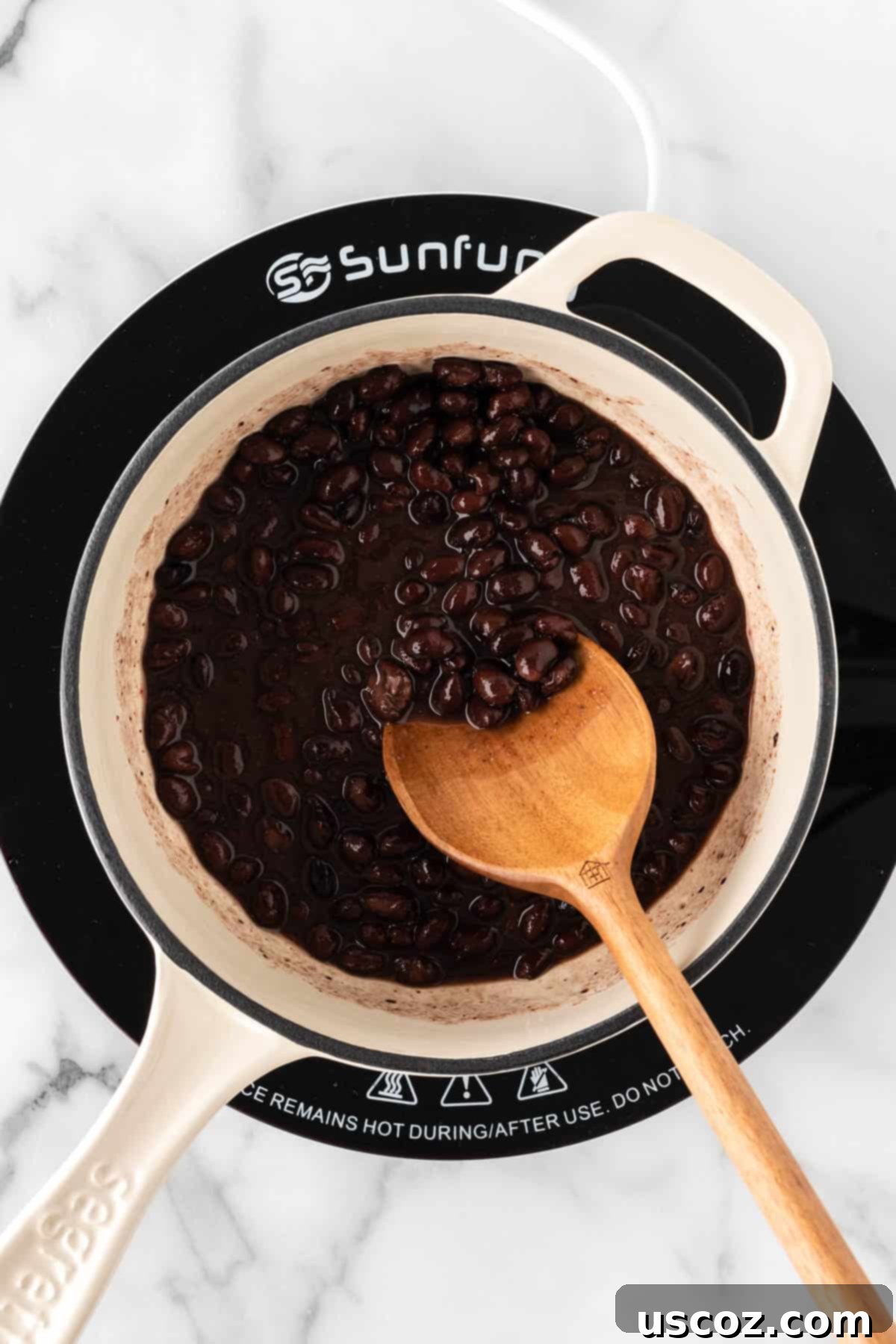 Low-Carb Cauliflower Rice Burrito Bowl 9 Stirring seasoned black beans in a saucepan as they warm up