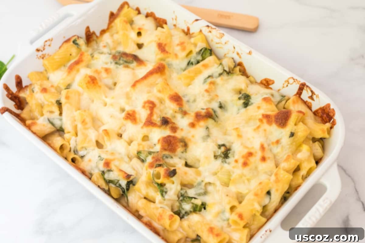 Creamy Spinach Artichoke Pasta Casserole 3 Spinach artichoke pasta bake in a pristine white baking dish, ready for serving