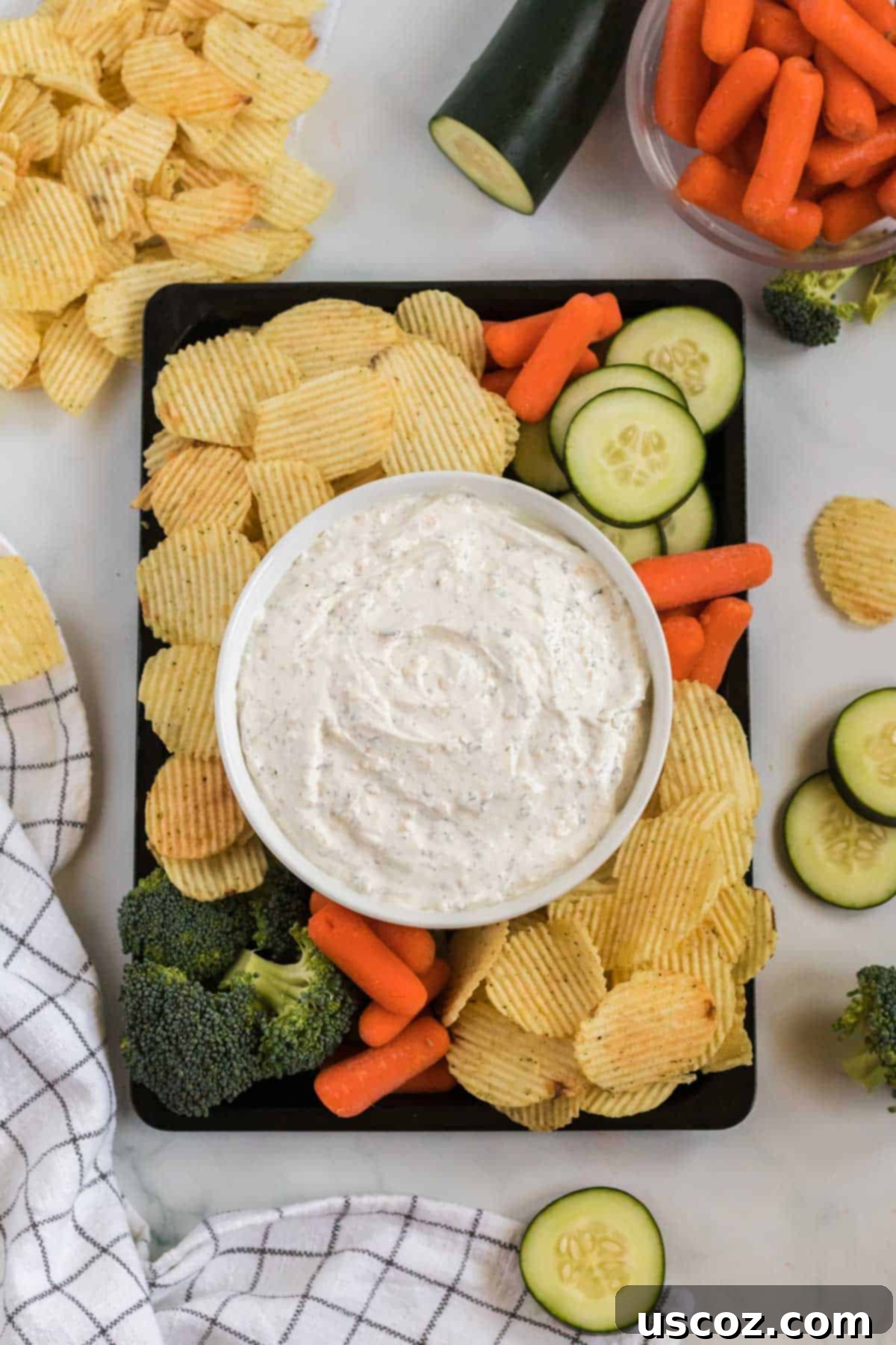 Dip Into Deliciousness 8 dip in a bowl surrounded by chips, broccoli, baby carrots, and cucumber