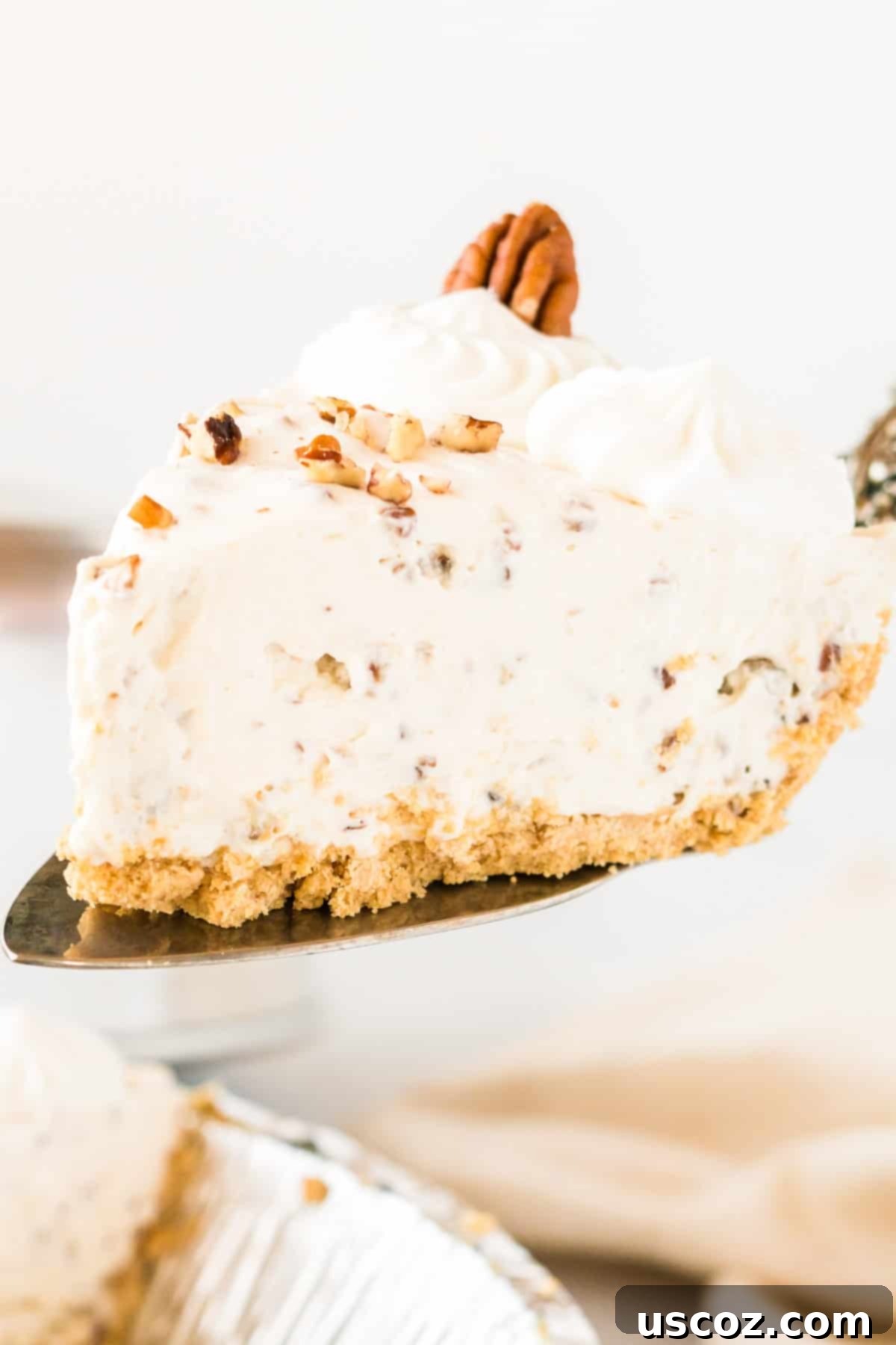Velvet Pecan Delight 8 A hand gently lifting a slice of pecan cream pie from the dish, showing its perfectly set filling.