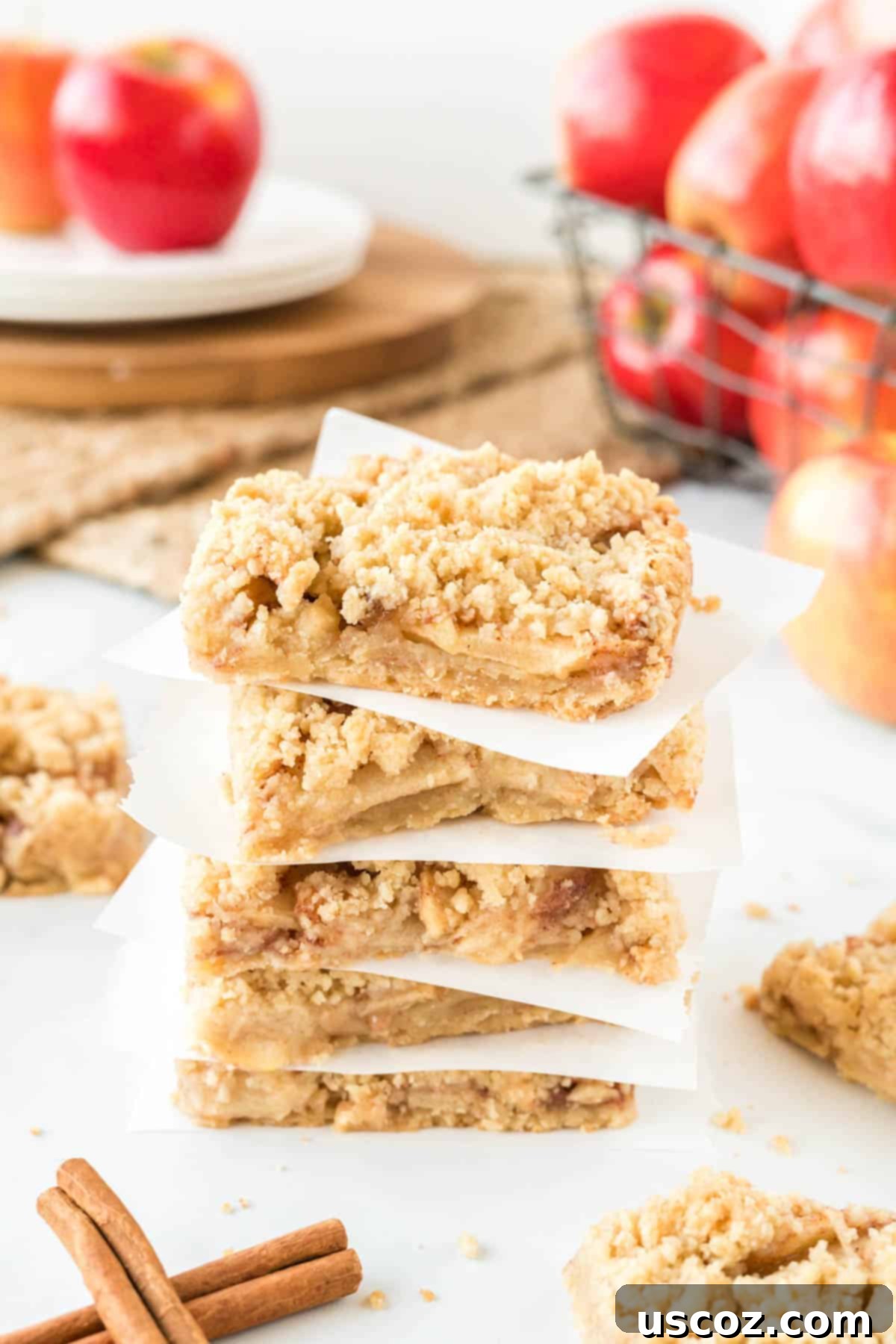 Cinnamon Apple Crumble Bars 11 More homemade apple crisp bars stacked with parchment paper, perfect for sharing