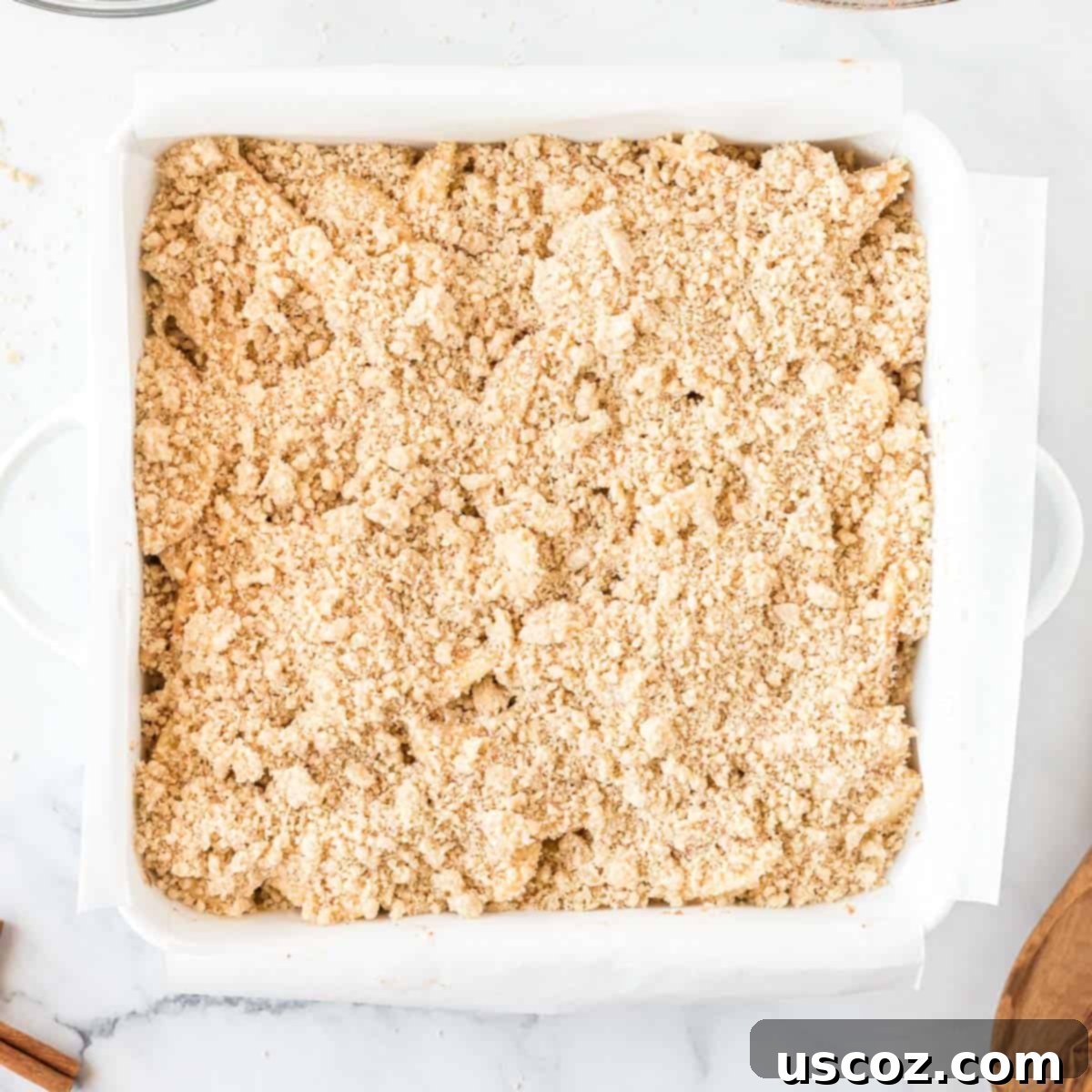 Cinnamon Apple Crumble Bars 9 Crumb topping generously sprinkled over apple crisp bars in a baking pan, ready for final bake