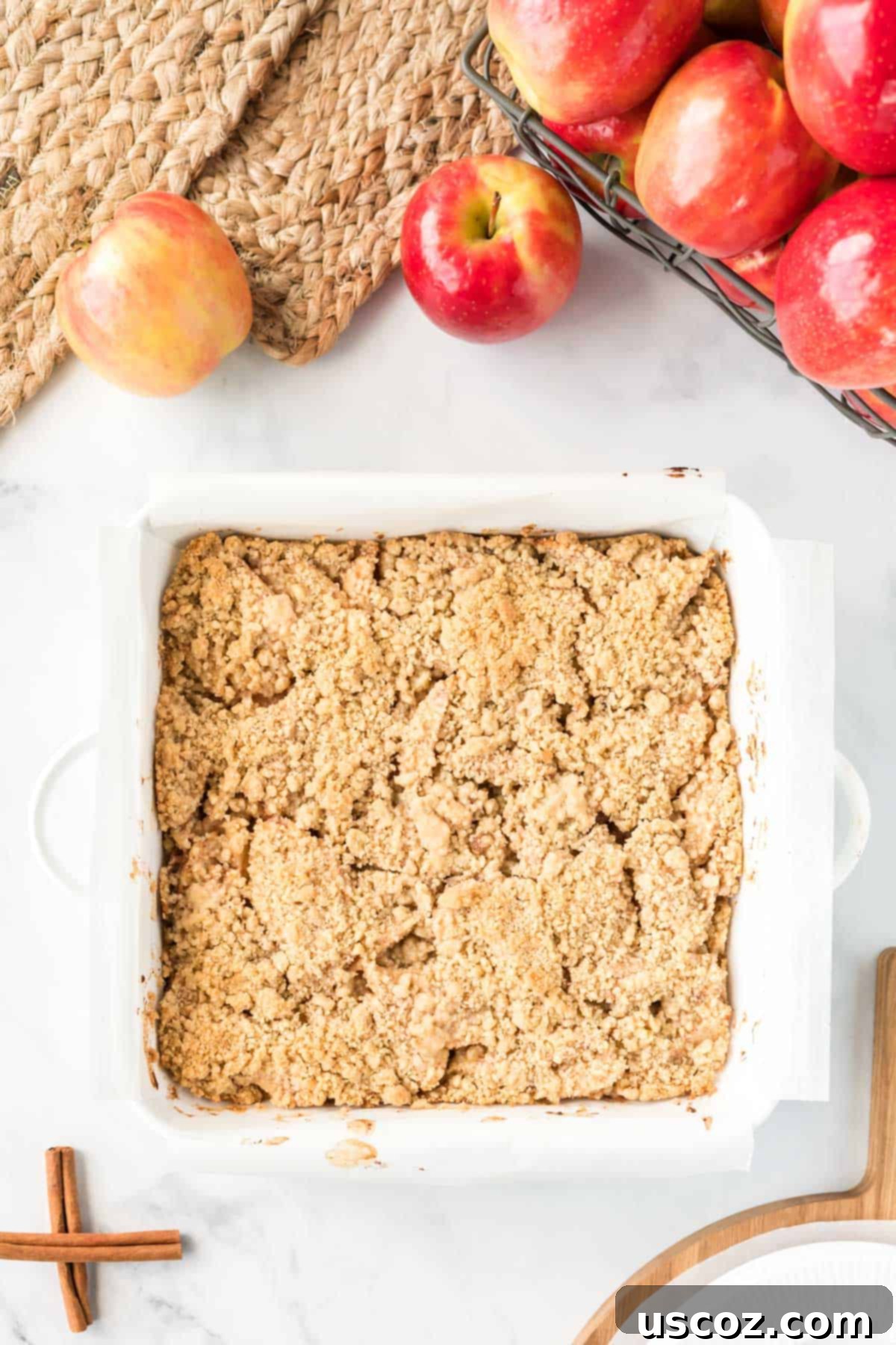 Cinnamon Apple Crumble Bars 10 Baked apple crisp bars in a white square baking dish, cooling down
