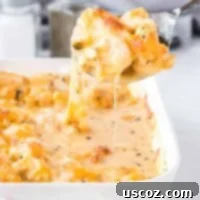 Golden Cheesy Cauliflower 10 A spoon scooping creamy cheesy cauliflower from the baking dish, highlighting the texture and melted cheese.