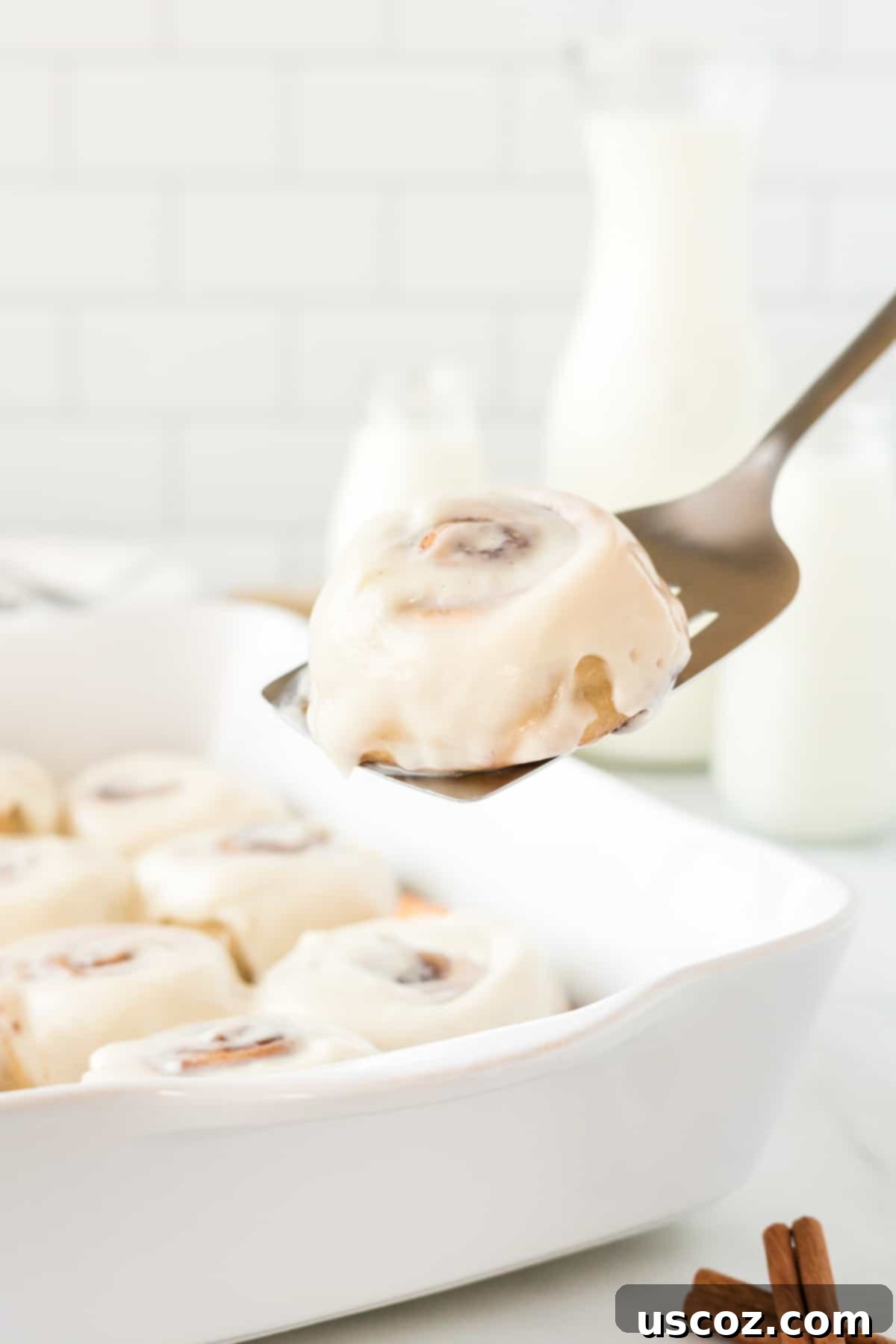 Effortless Cinnamon Swirls 15 spatula lifting a perfect no-rise cinnamon roll from the dish