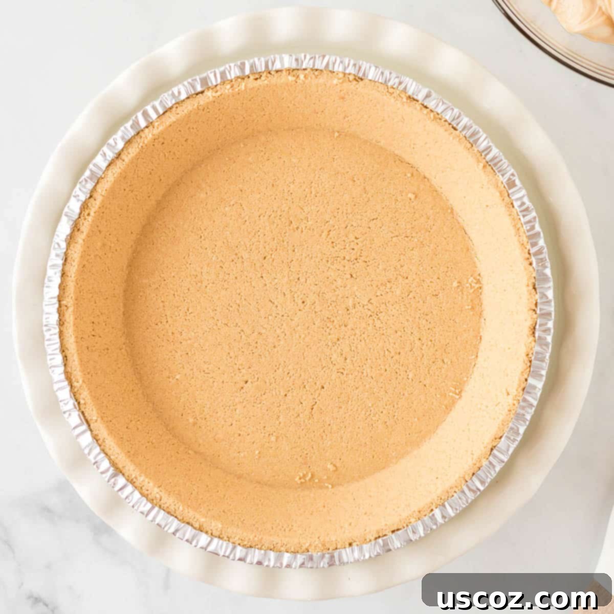 Simple No-Bake Peanut Butter Delight 10 A golden brown graham cracker crust sitting in a pie dish, ready for filling.