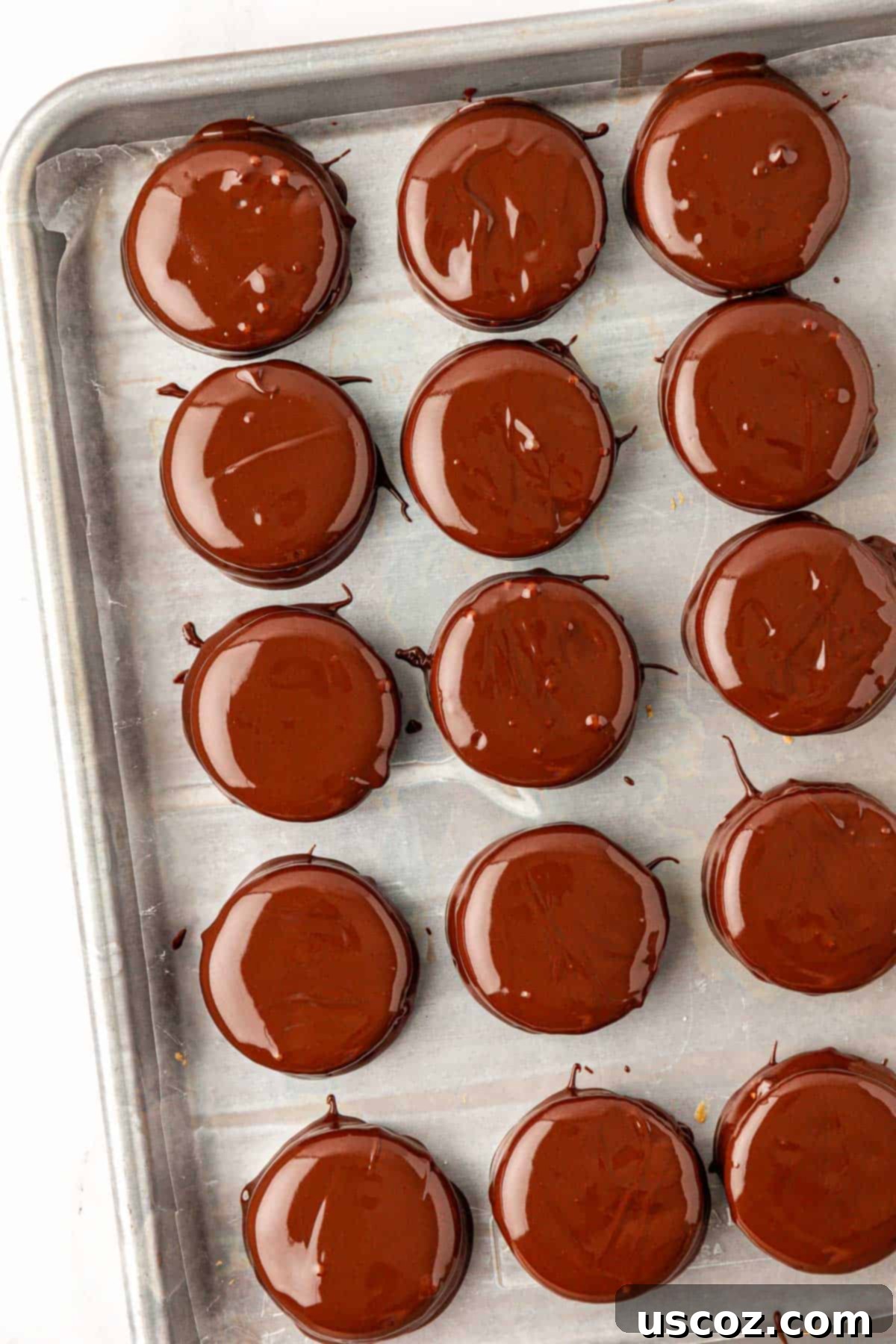 Irresistible Ritz Cookie Bites 11 Multiple chocolate-dipped Ritz Cracker Cookies cooling on a baking sheet, some with sprinkles.