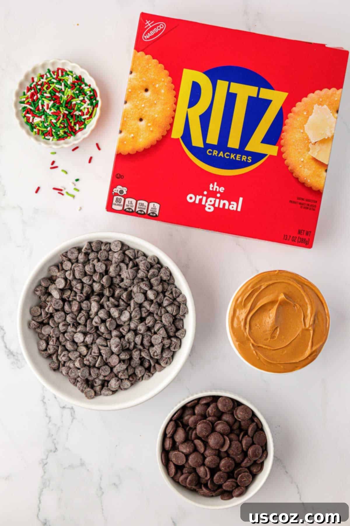 Irresistible Ritz Cookie Bites 4 Ingredients for Ritz Cracker Cookies laid out: Ritz crackers, peanut butter, dark and semi-sweet chocolate chips, and sea salt.