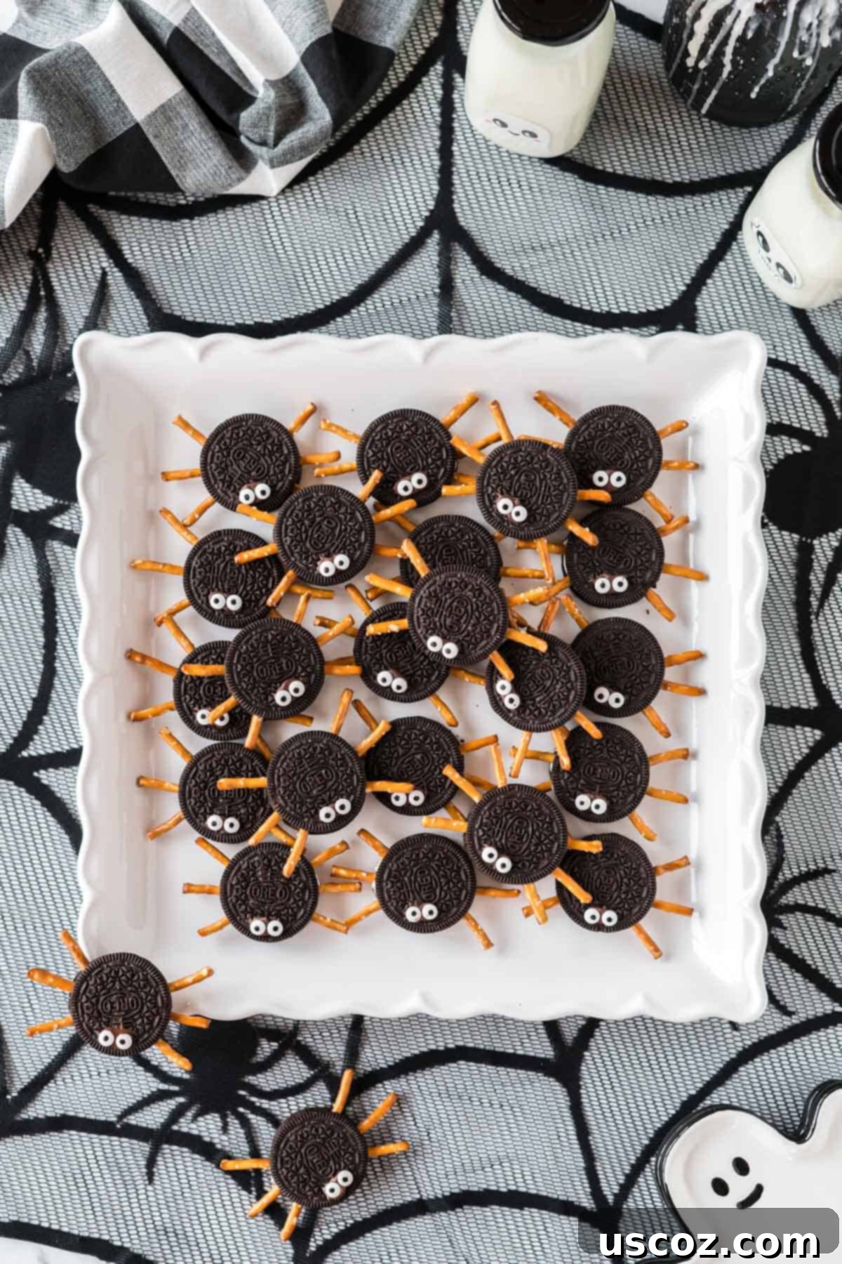 Eight-Legged Oreo Delights 13 A tray filled with finished Oreo spider cookies, showcasing their intricate pretzel legs and comical googly eyes on a white serving tray.