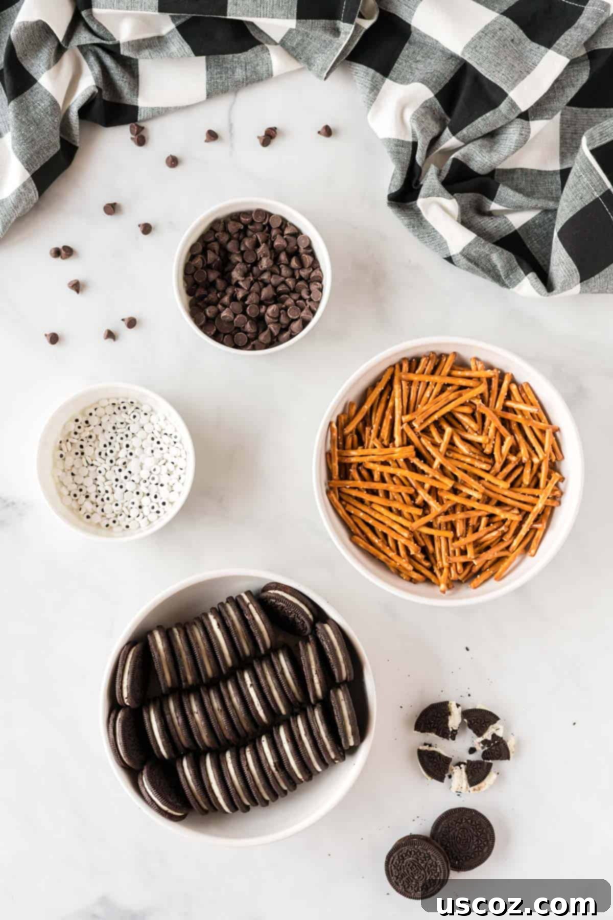 Eight-Legged Oreo Delights 4 Ingredients laid out to make easy Oreo spider cookies: Oreos, pretzel rods, chocolate chips, and edible googly eyes.