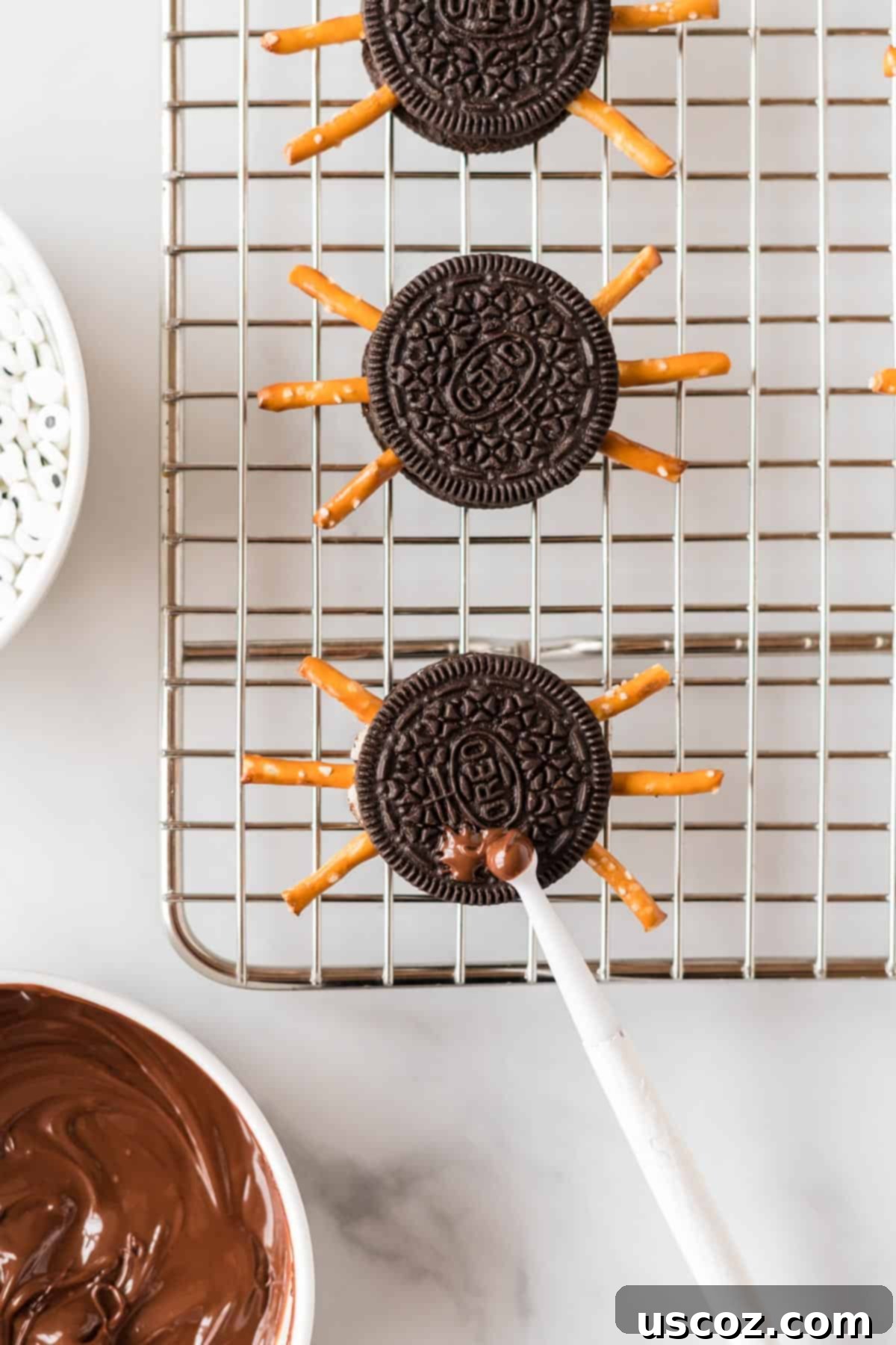 Eight-Legged Oreo Delights 9 A toothpick applying a small dab of melted chocolate to an Oreo cookie, preparing for the googly eyes for a spider treat.