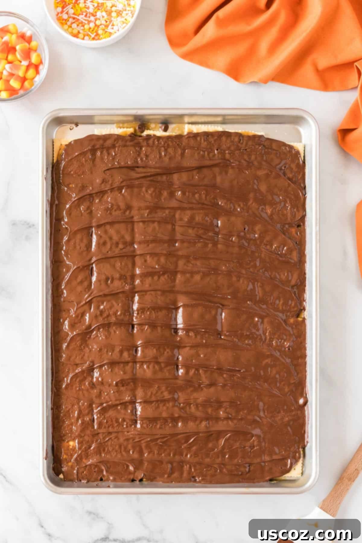 Spooky Halloween Crack 9 Melted chocolate smoothed out evenly over the sheet pan, creating a perfect top layer for the Halloween crack candy.