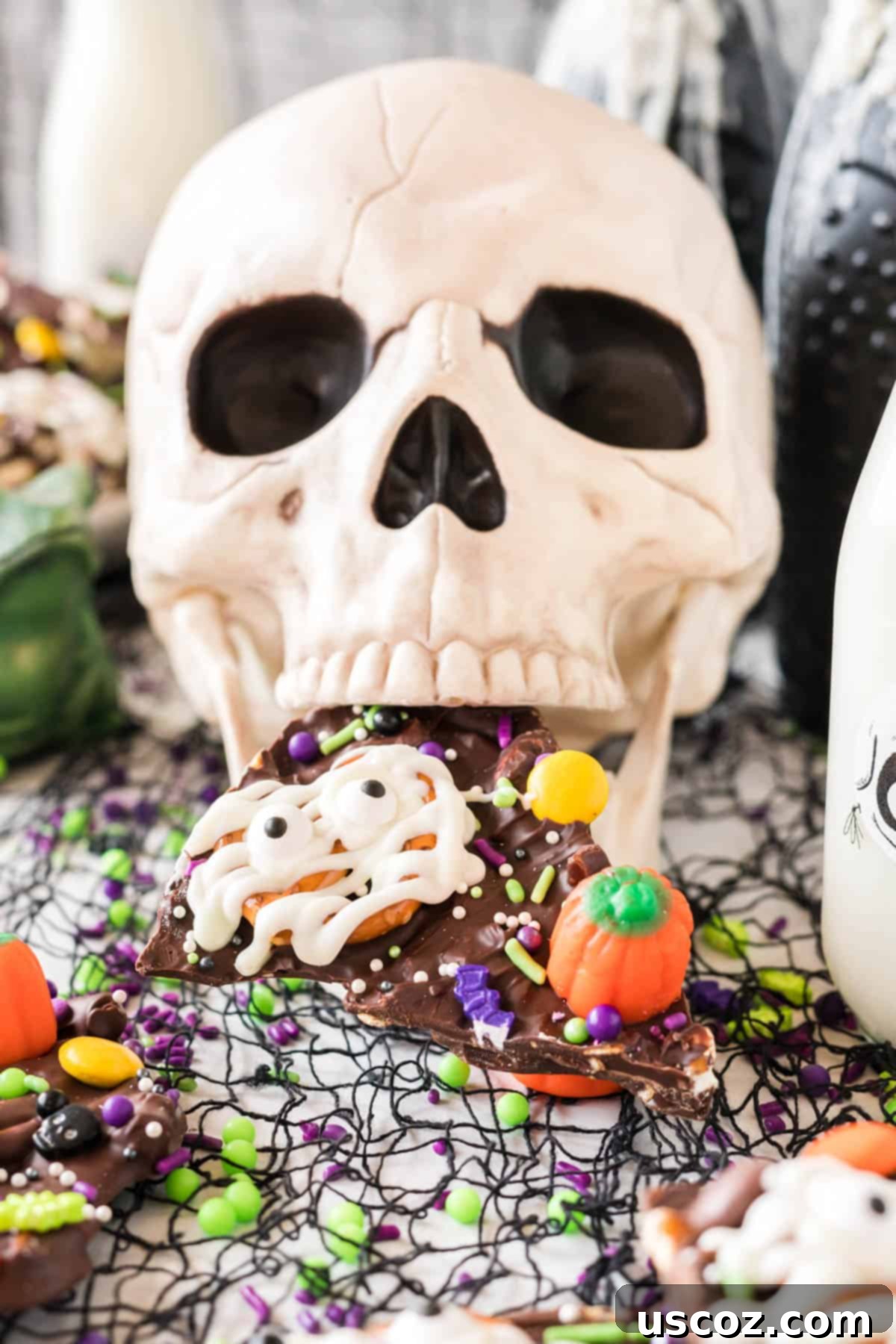 Monster Mash Bark 16 decorative skull holding a piece of halloween bark in its mouth