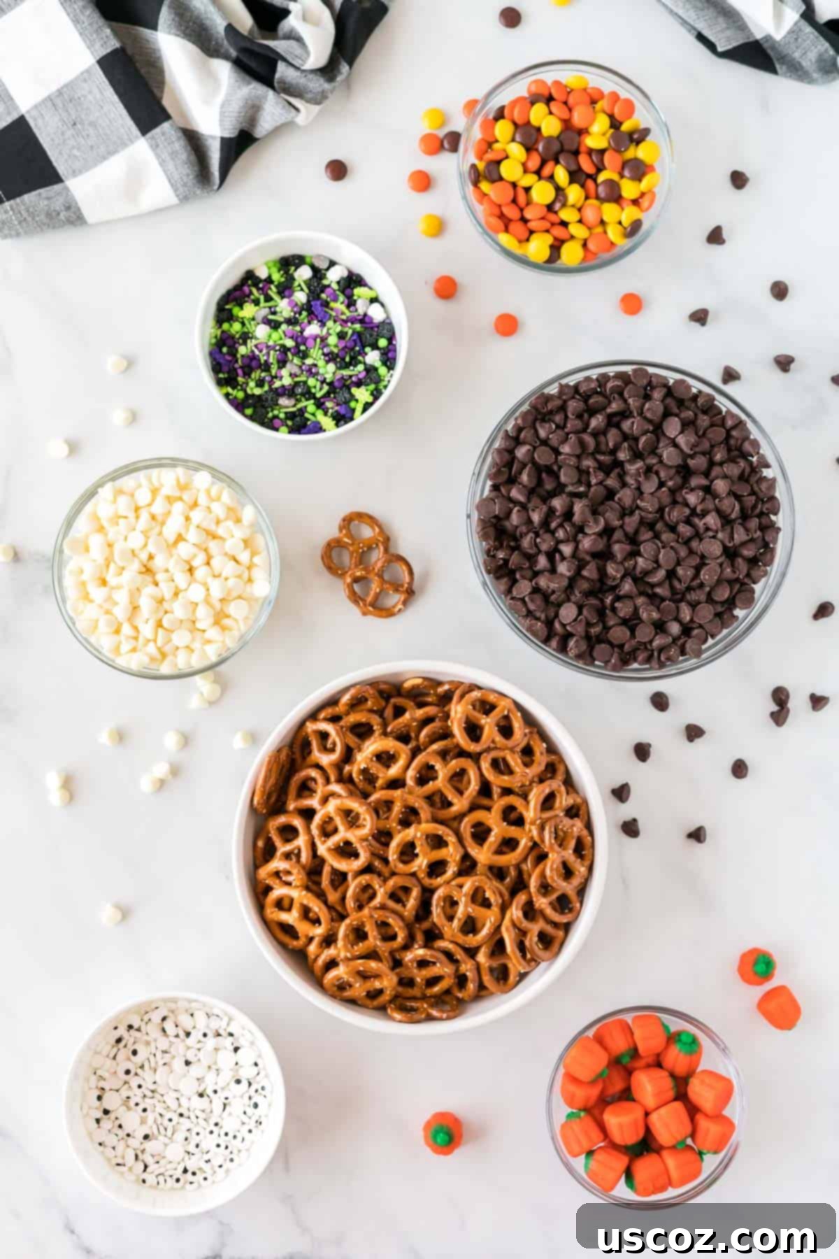 Monster Mash Bark 3 ingredients laid out to make halloween bark, including chocolate chips, pretzels, and various candies