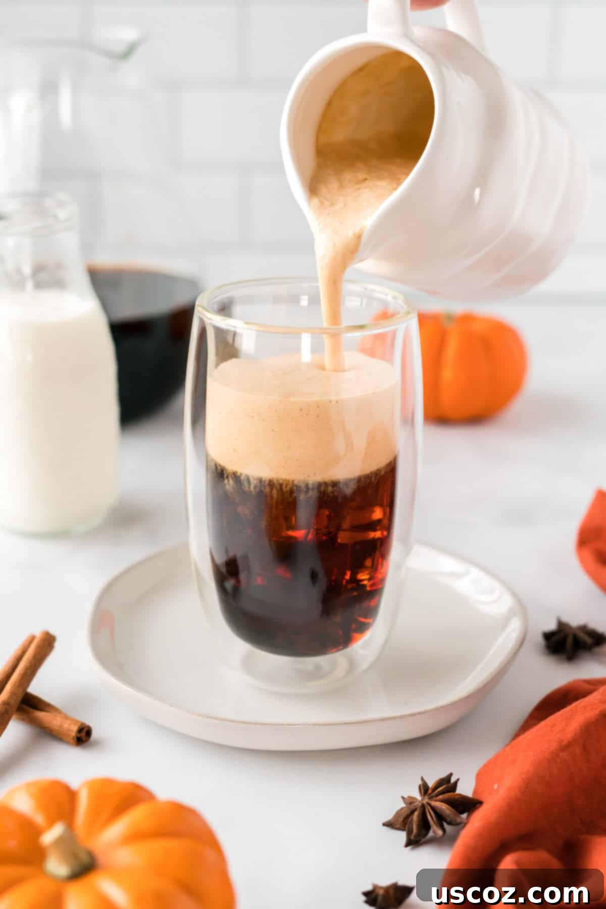 Spiced Pumpkin Cold Brew 2 Pouring rich pumpkin cream over dark cold brew coffee into a glass with ice