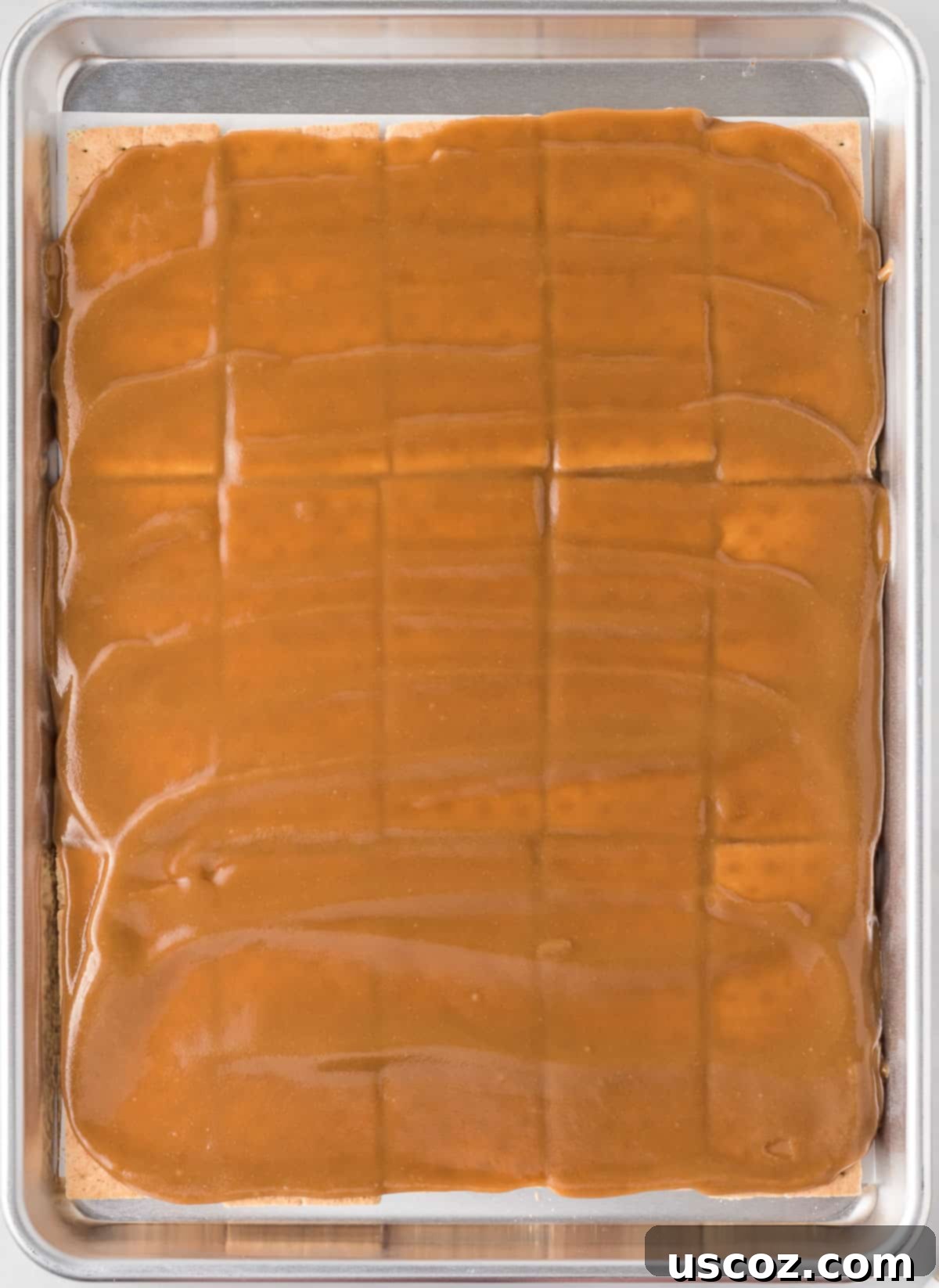 Golden Graham Toffee 8 spreading out the hot toffee mixture evenly over the graham crackers on the baking sheet