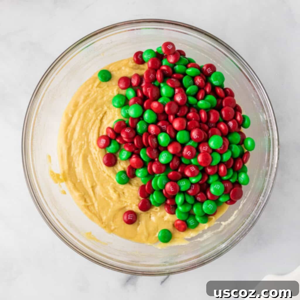 Effortless Holiday Cake Mix Cookies 7 Adding colorful Christmas M&M's to the prepared cookie batter