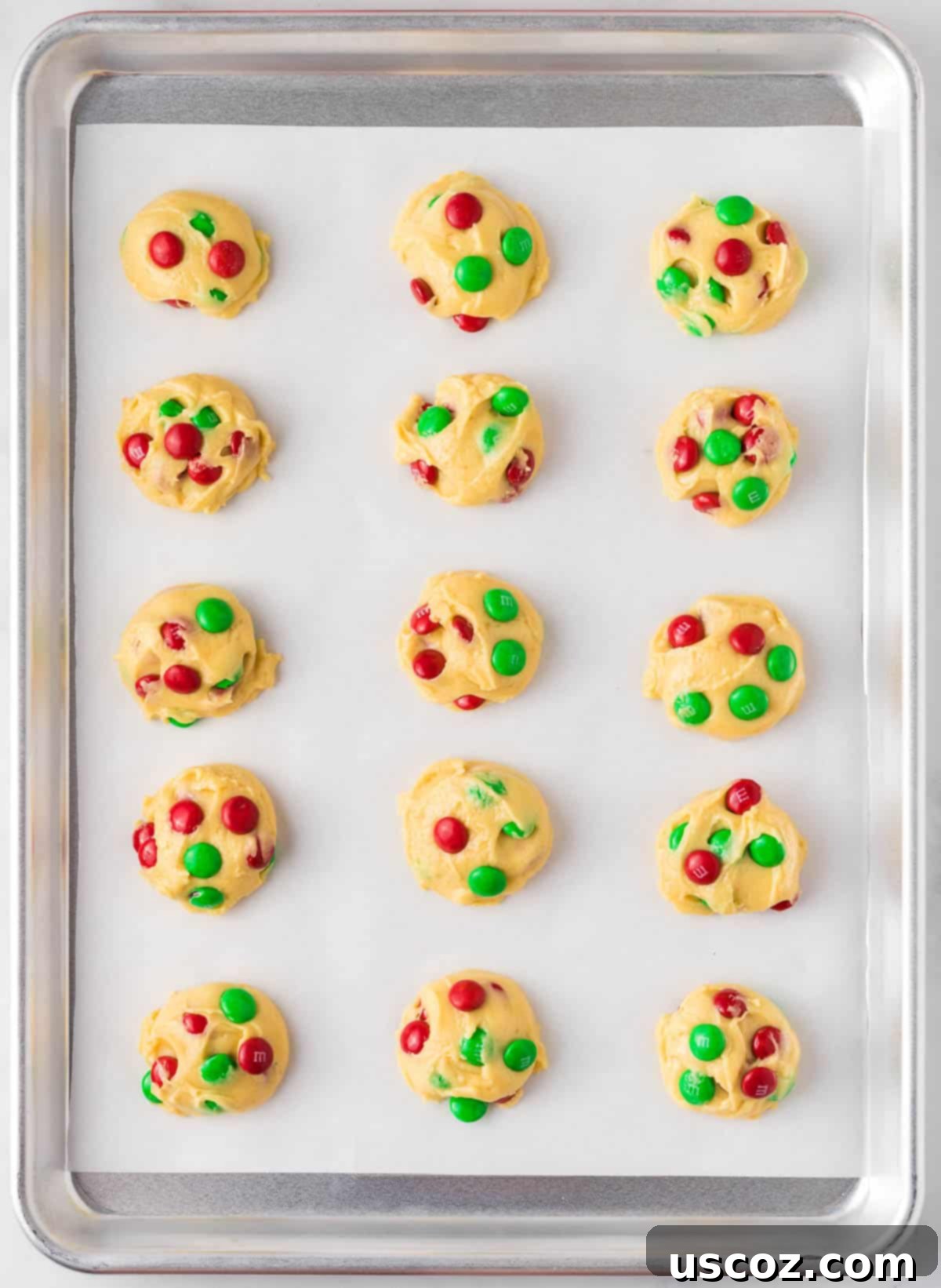 Effortless Holiday Cake Mix Cookies 9 Scooped Christmas cookie dough balls topped with extra M&M's on a baking sheet, ready for the oven