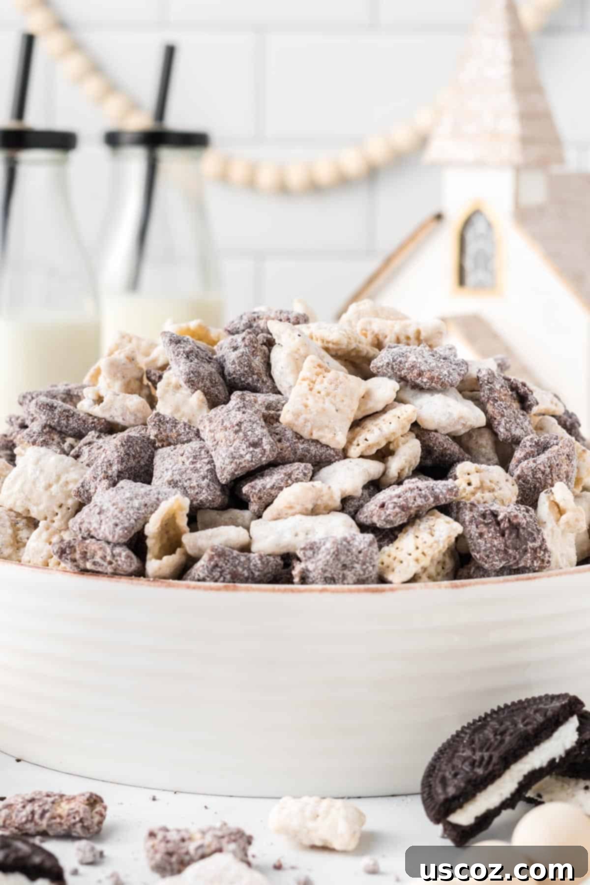 Cookies and Cream Dream Bites 3 Cookies and Cream Muddy Buddies artfully arranged in a large festive serving bowl, with twinkling Christmas decorations subtly blurred in the background, hinting at holiday cheer.