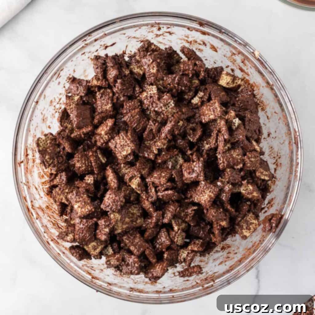 Cookies and Cream Dream Bites 9 Rice Chex cereal in a bowl being gently mixed with melted semi-sweet chocolate, ensuring an even coating.