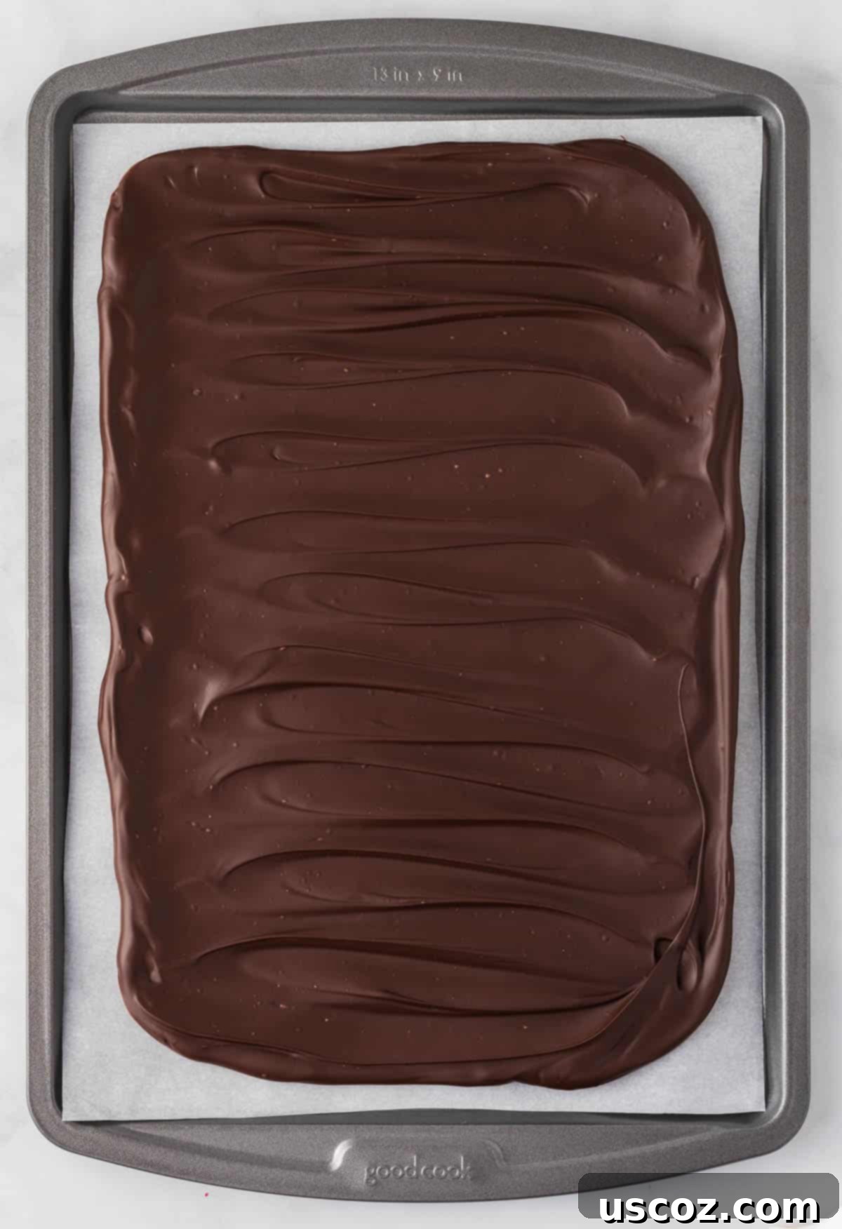 Decadent Mint Chocolate Bark 12 The hardened dark chocolate layer on a baking sheet, providing a solid foundation for the next layer of peppermint bark.