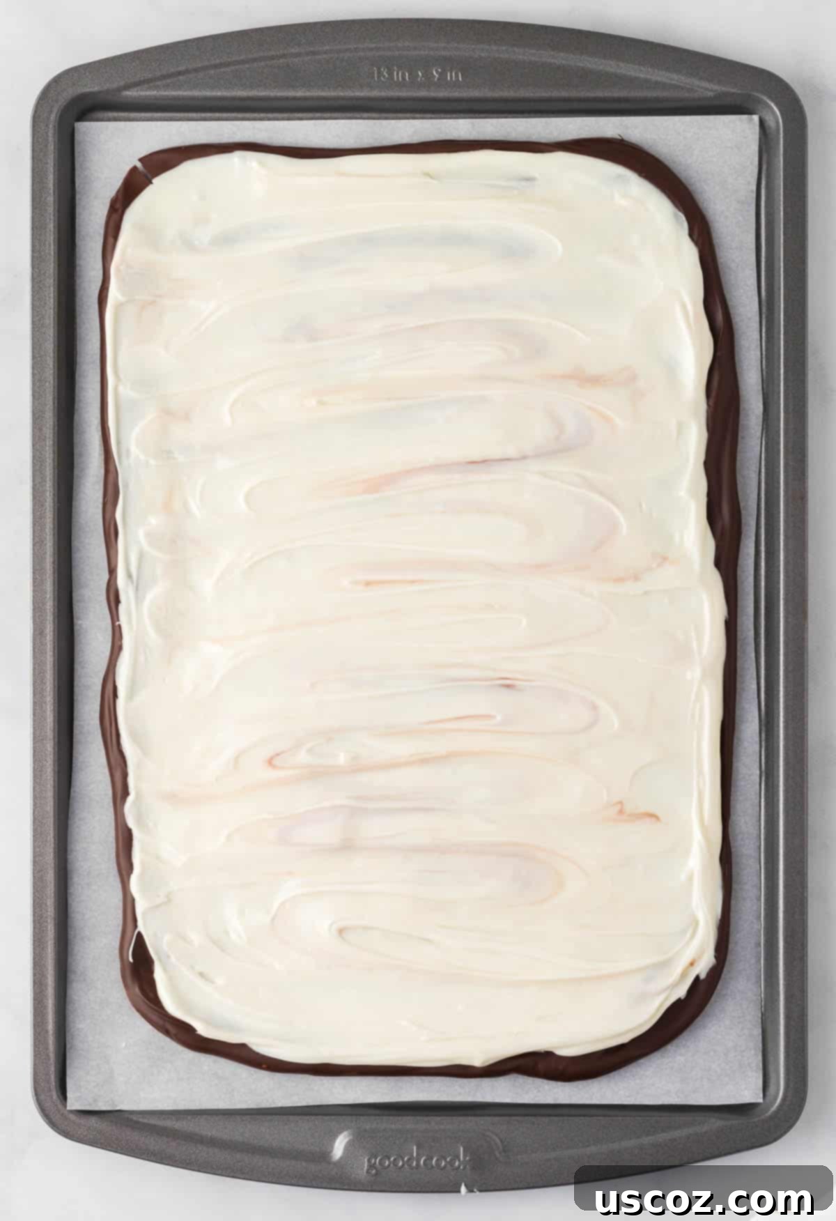 Decadent Mint Chocolate Bark 13 Spreading smooth, melted white chocolate over the hardened dark chocolate layer on a baking sheet.