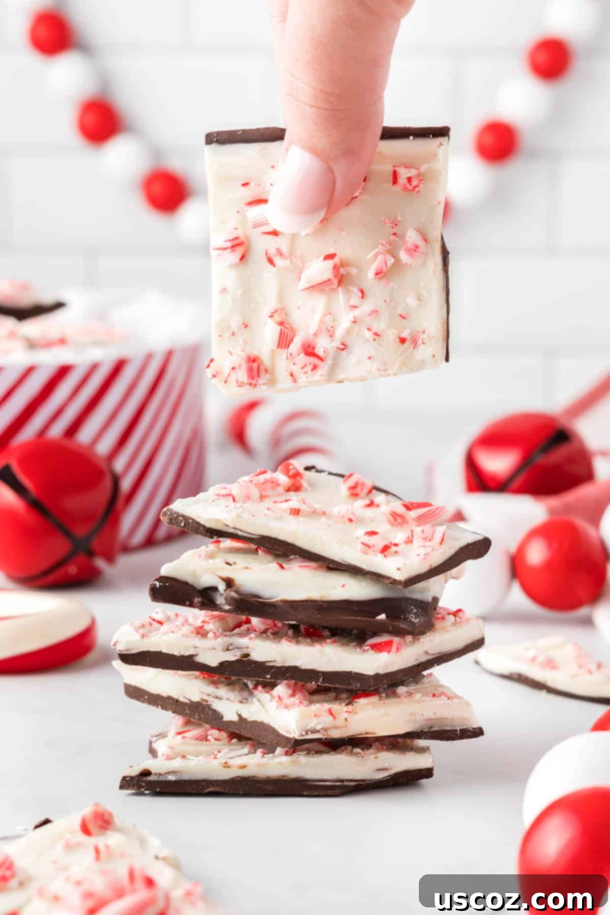 Decadent Mint Chocolate Bark 3 Stacked pieces of delicious chocolate peppermint bark, showcasing the dark and white chocolate layers with crushed candy cane topping.