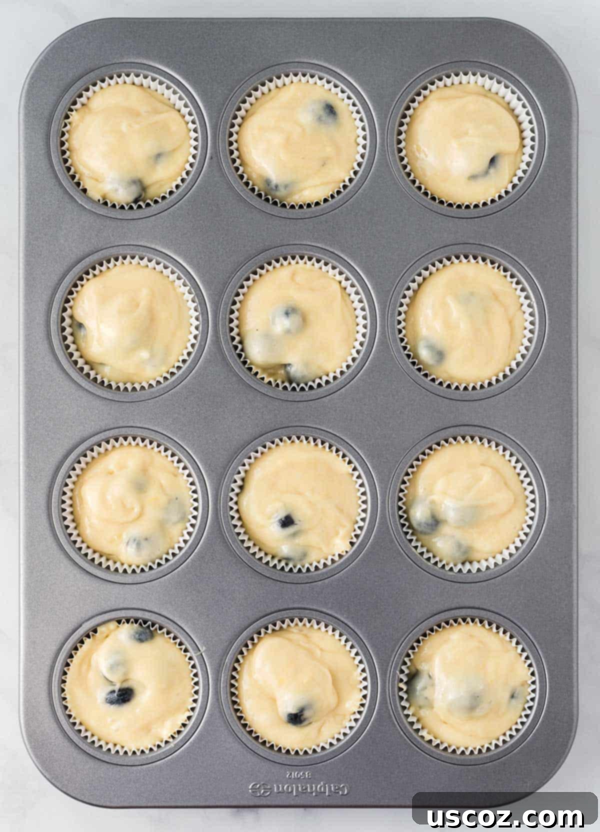 Effortless Cake Mix Blueberry Muffins 13 Muffin batter scooped into muffin liners in a tin