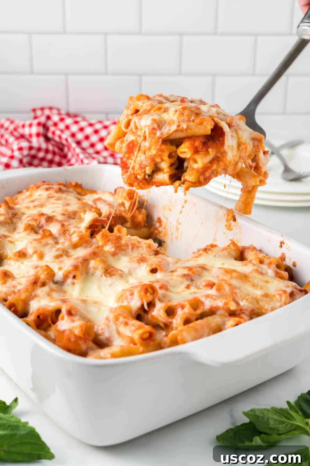 Cheesy Meatless Ziti Bake 17 Scooping a generous portion of cheesy, layered vegetarian baked ziti from the casserole dish