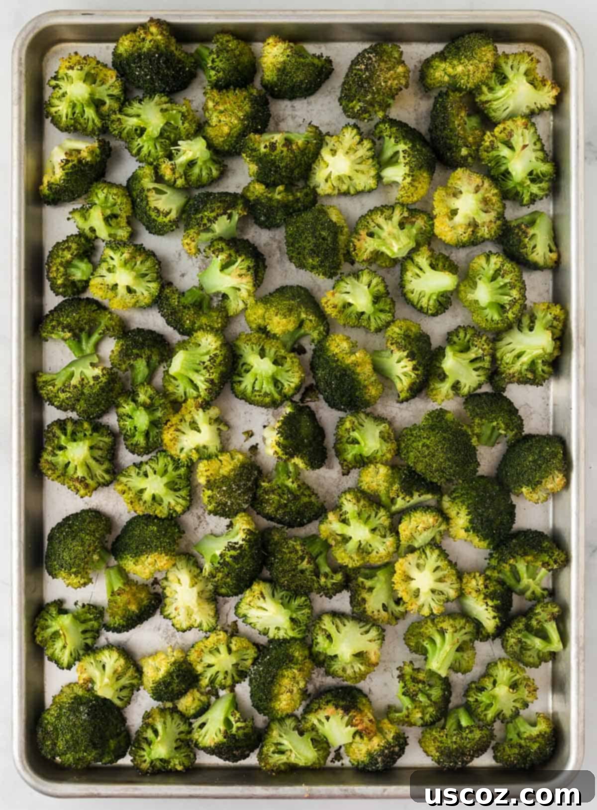 Parmesan Roasted Broccoli 9 Freshly grated parmesan cheese being sprinkled over partially roasted broccoli on a baking sheet