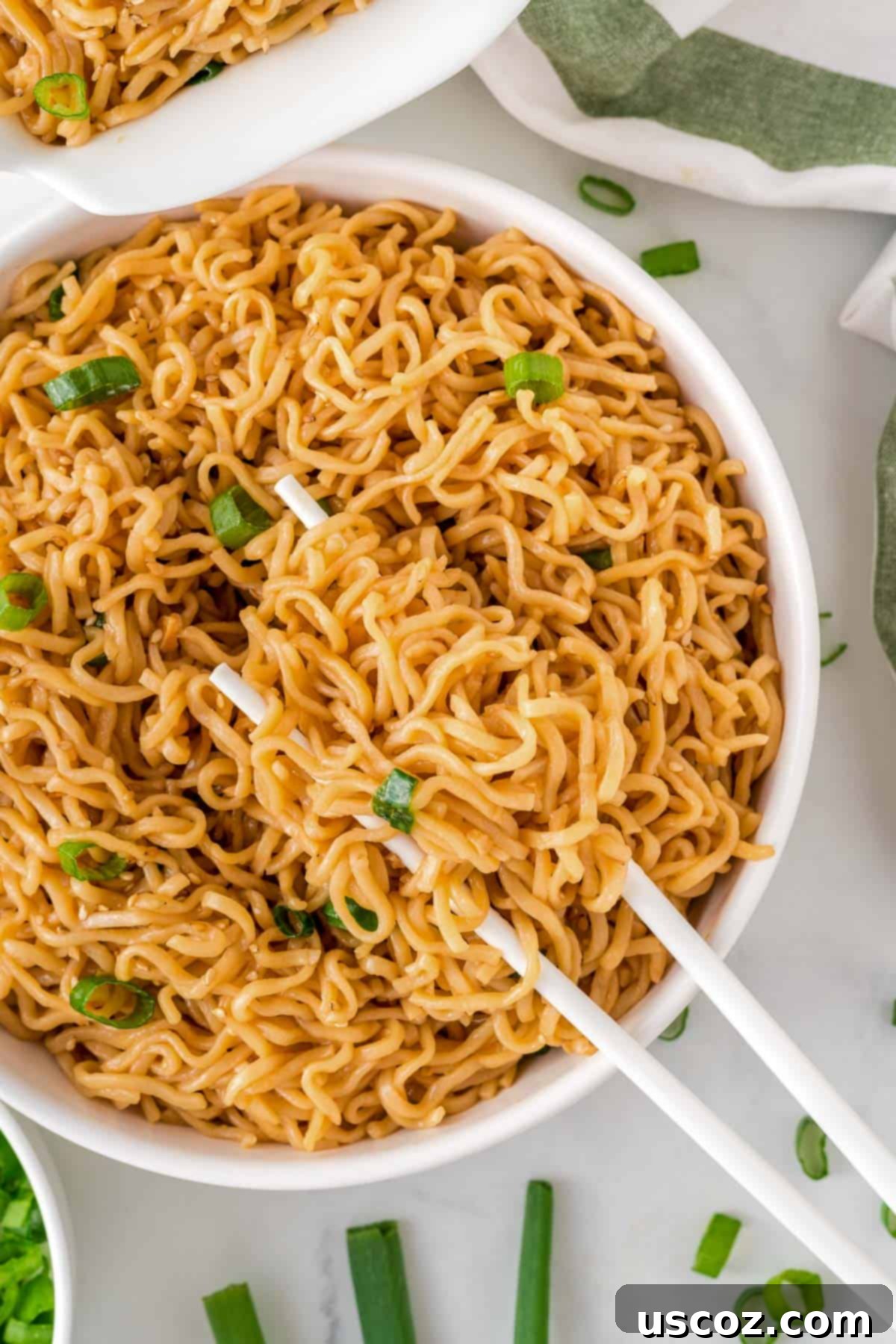 Easy Sesame Garlic Ramen 2 Chopsticks expertly holding a tangle of flavorful sesame garlic ramen noodles from a rustic bowl, showcasing the rich sauce and a hint of fresh green onions.