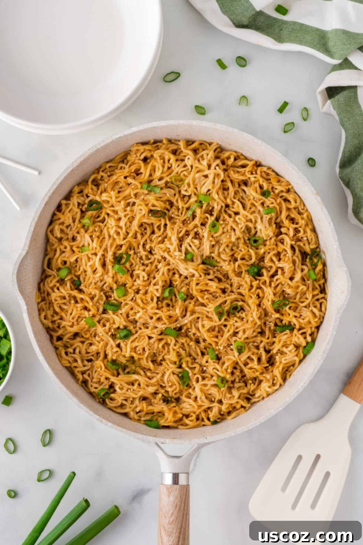 Easy Sesame Garlic Ramen 11 Garlic ramen noodles glistening in a skillet, beautifully garnished with fresh green onions, presenting a vibrant and appetizing view.